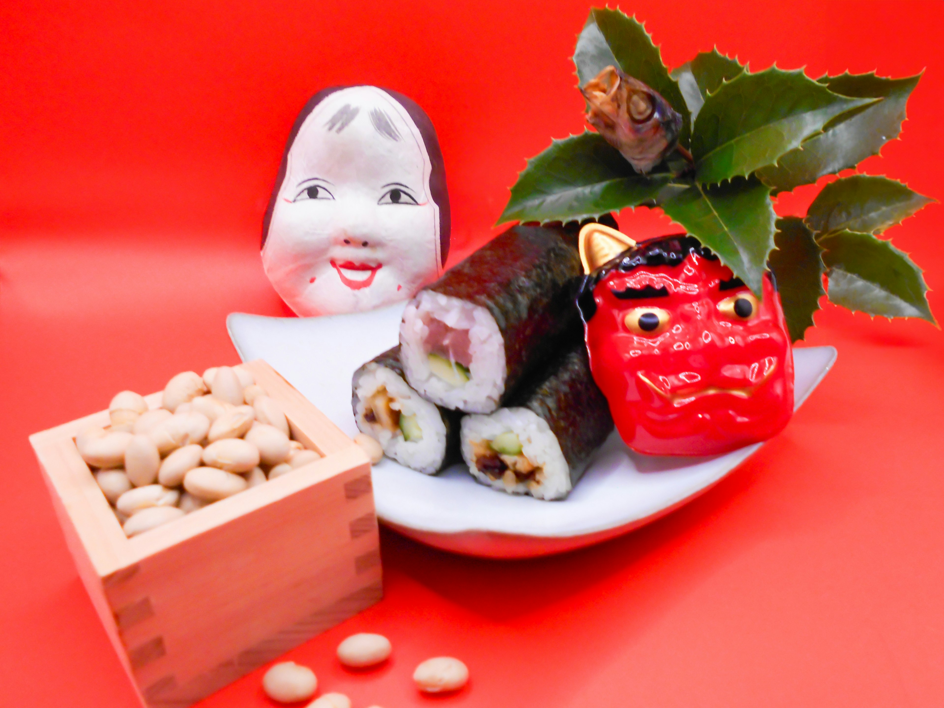 Imagen de sushi y muñecas tradicionales dispuestas sobre un fondo rojo