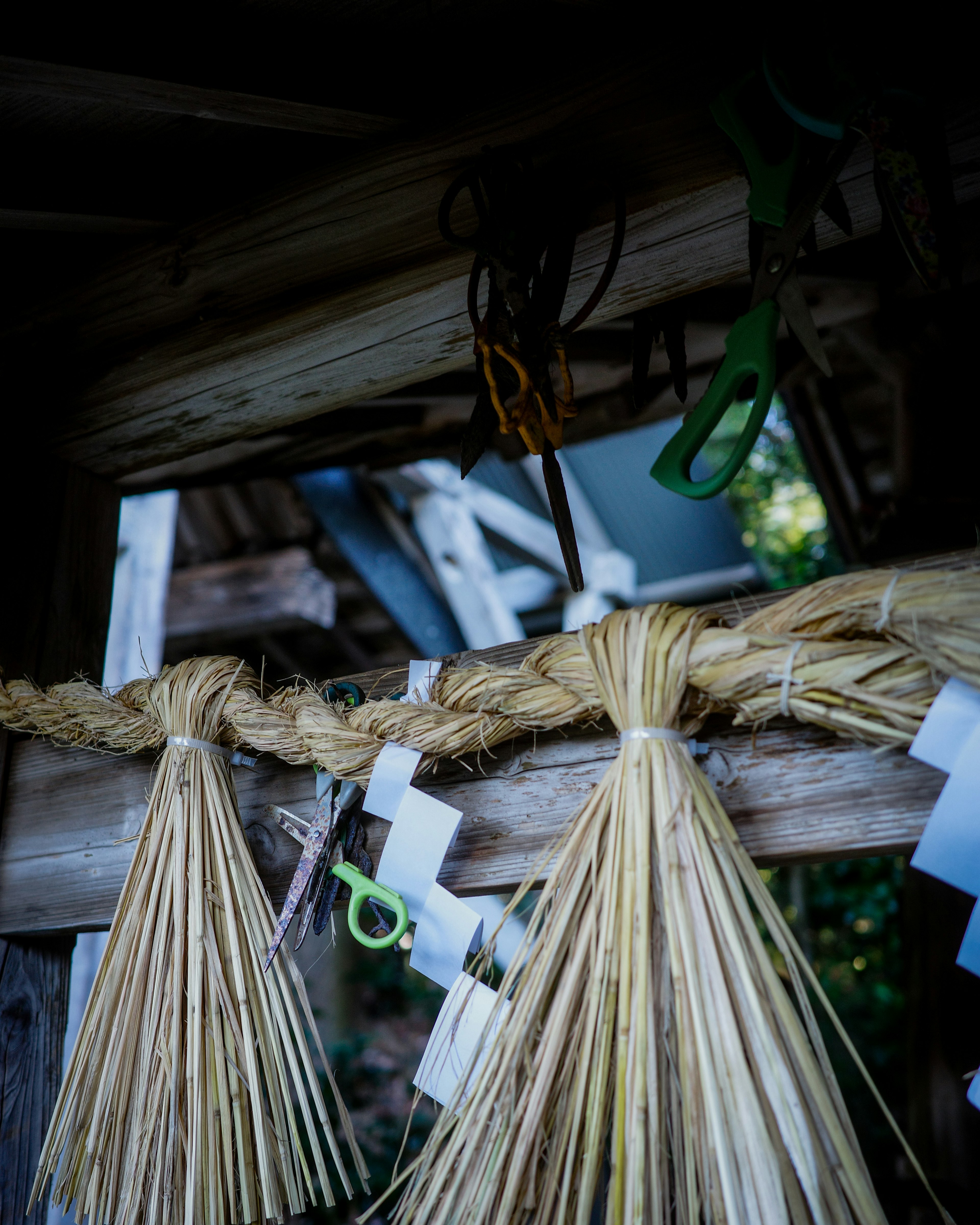 Woven straw decoration with scissors hanging on a wooden structure