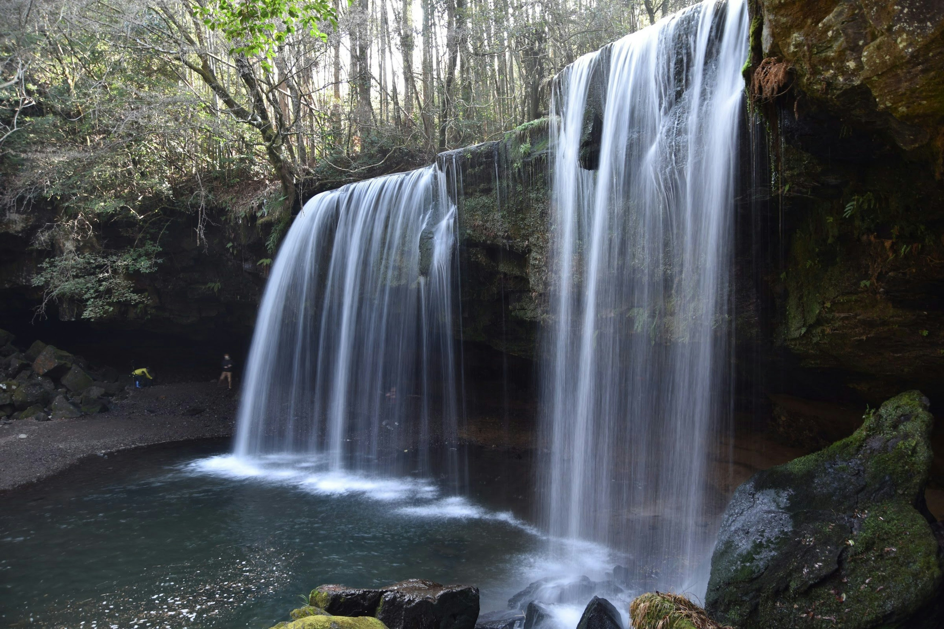 Una hermosa cascada que fluye en un paisaje natural con árboles verdes de fondo y gotas de agua brillantes