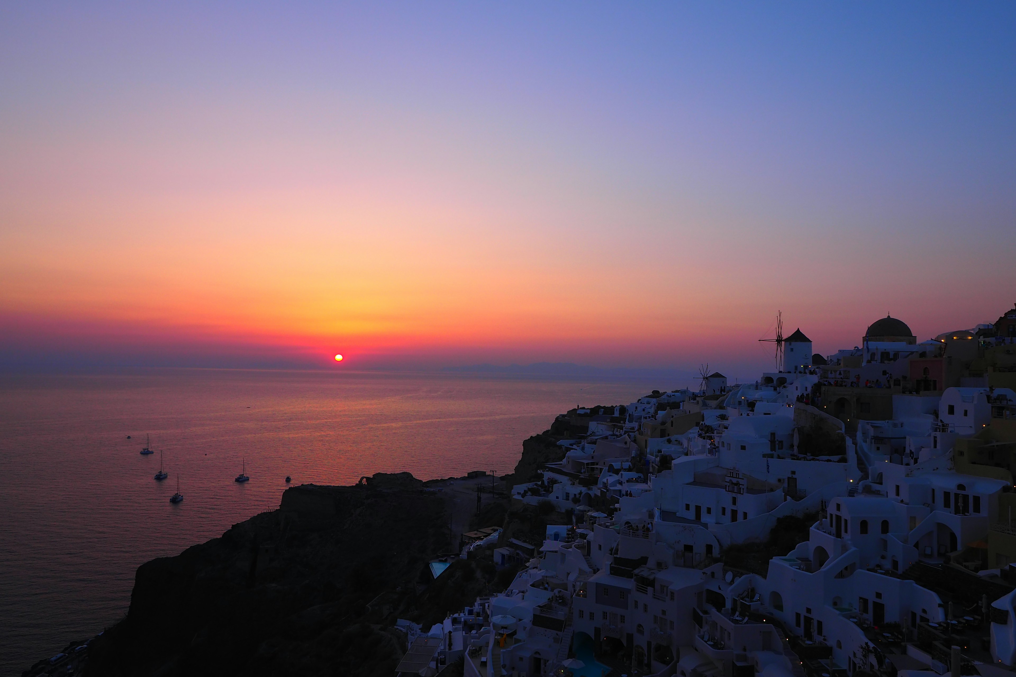 Coucher de soleil sur la mer avec des bâtiments blancs à Santorin