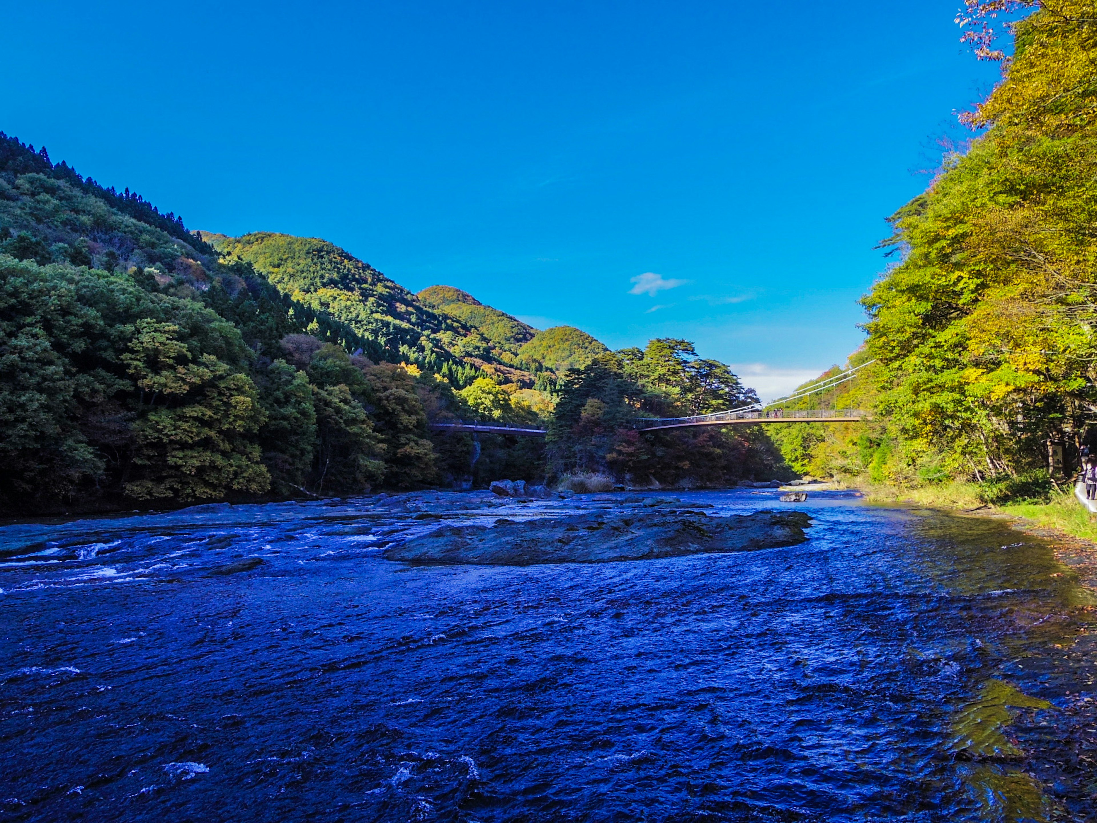 Scenic river landscape surrounded by green mountains and blue sky