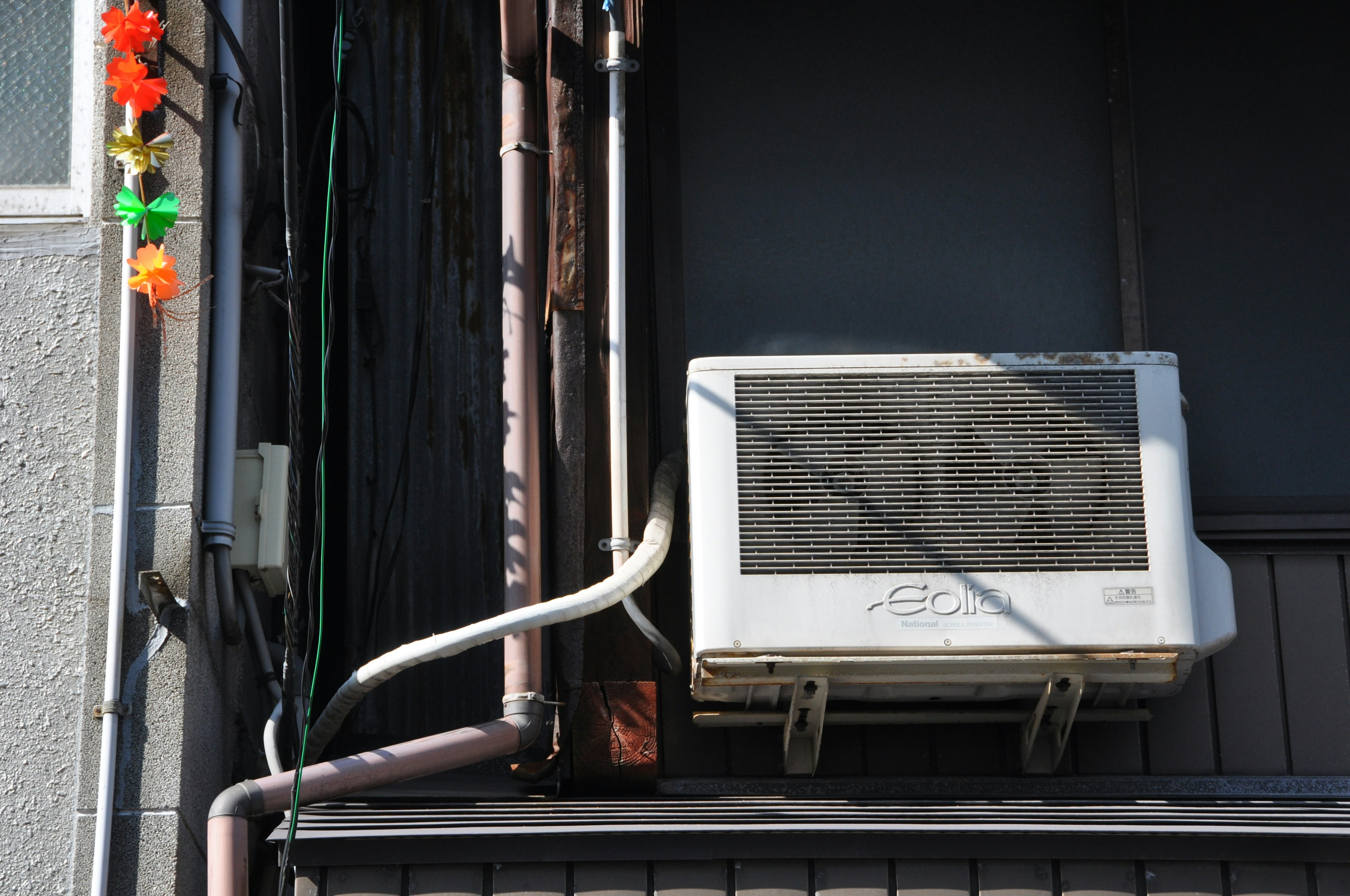 Air conditioning unit mounted on an exterior wall with visible piping