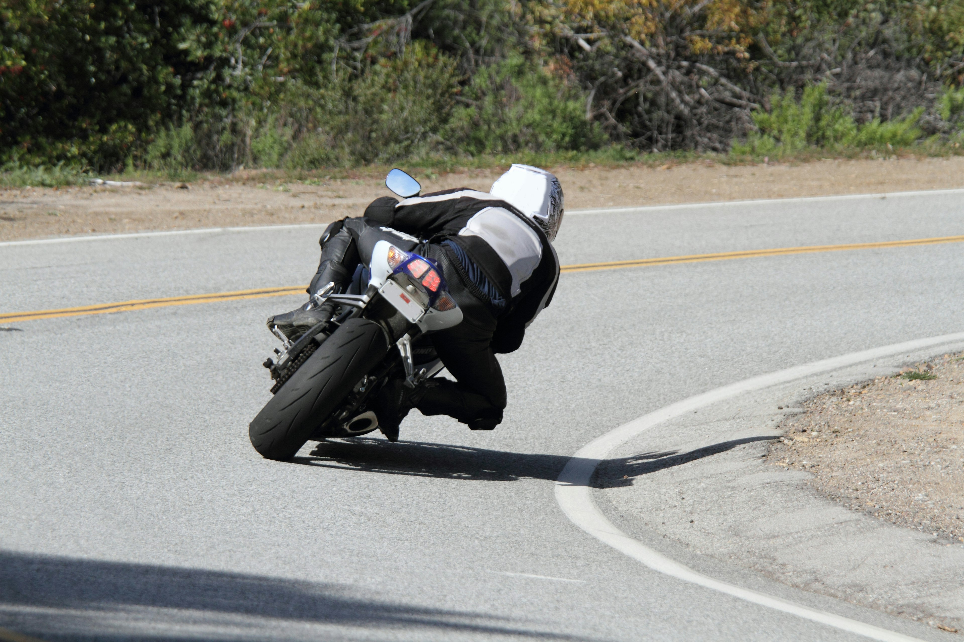 Motorcycle rider leaning into a curve on a winding road