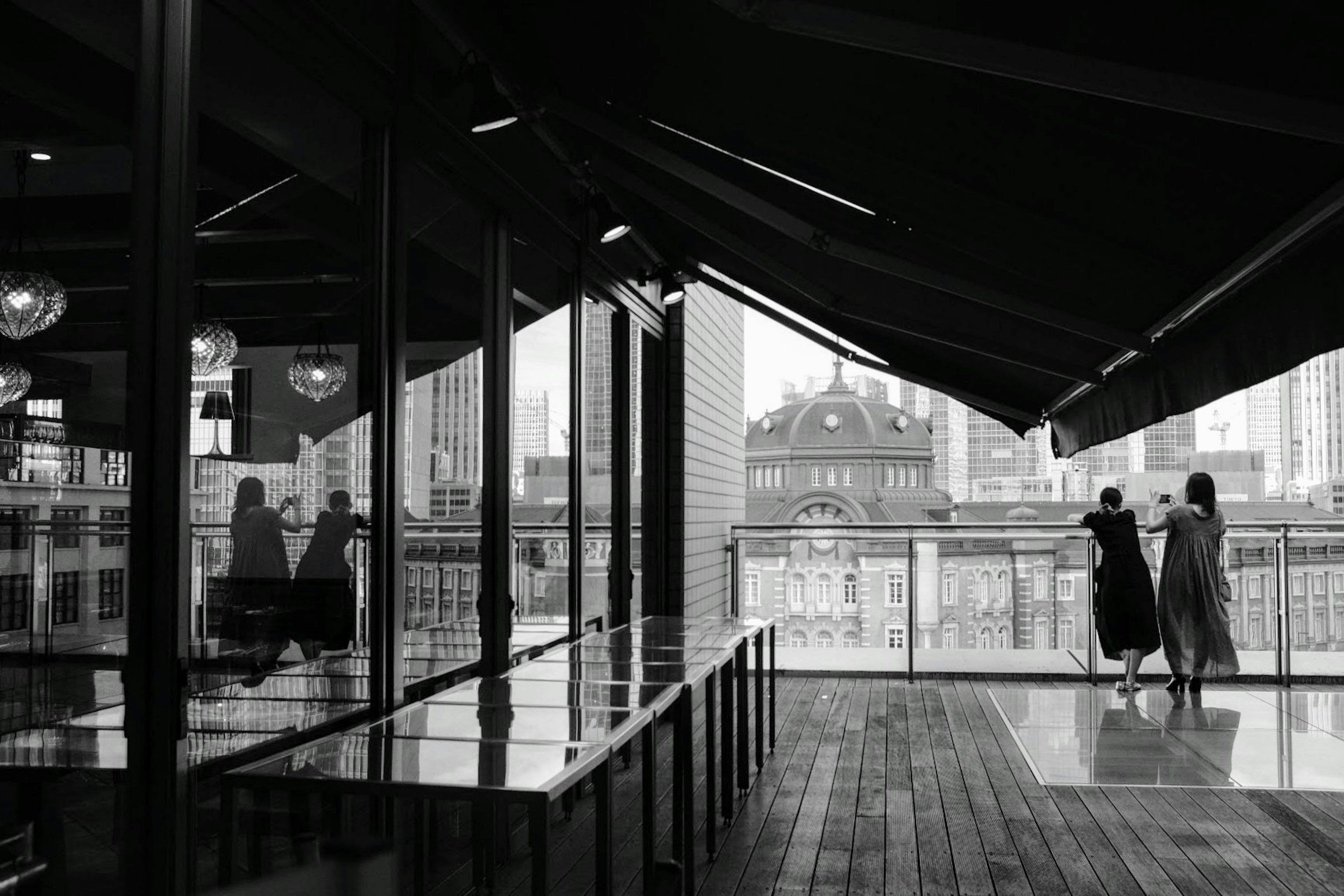 Silhouettes de deux femmes surplombant la ville depuis un balcon moderne