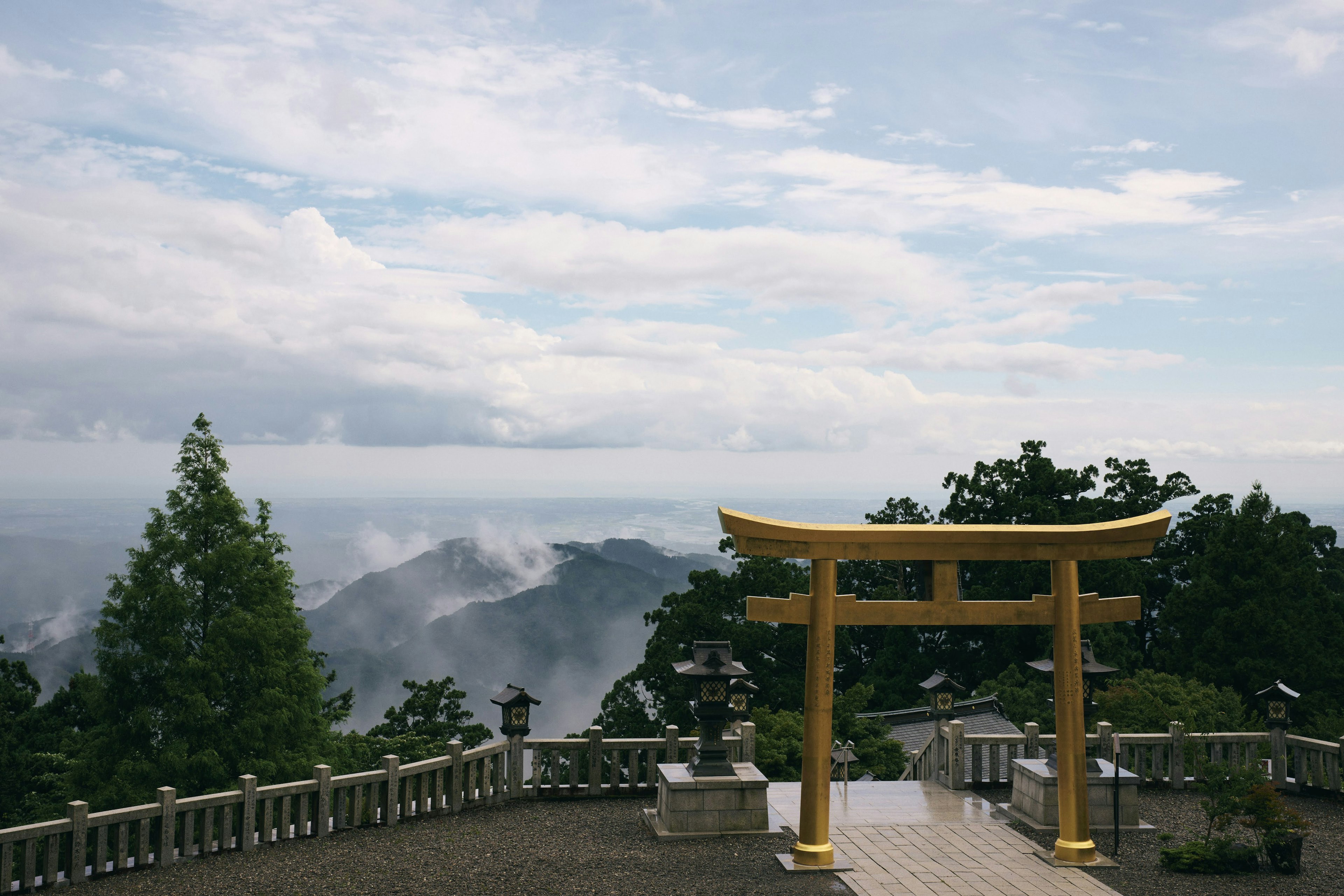 Japanese shrine with a golden torii gate and mountainous landscape