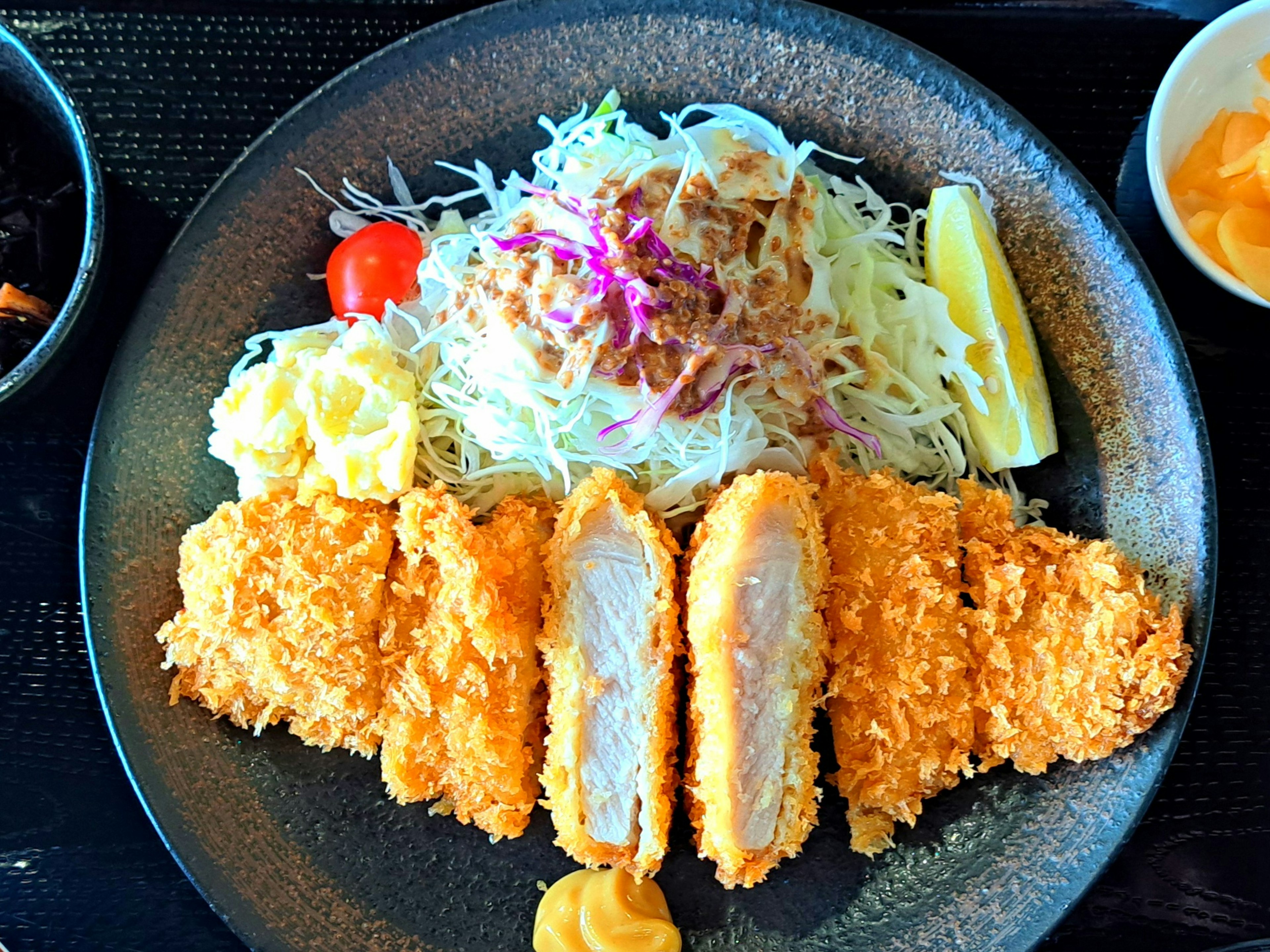 Piatto di cotoletta di pollo croccante servita con insalata di cavolo e salse