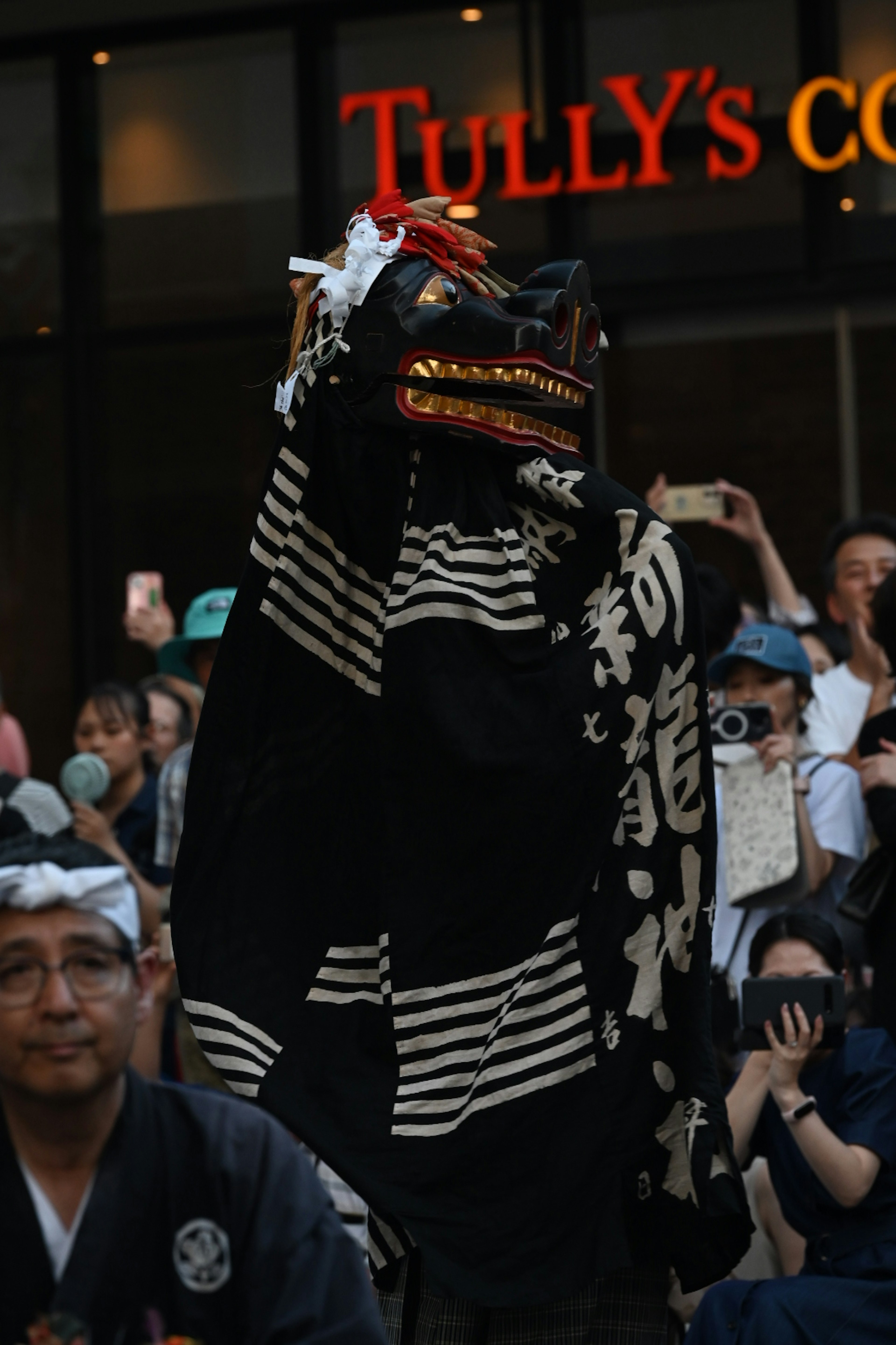 Ein Darsteller in einem traditionellen schwarz-weiß gestreiften Outfit tanzt vor einem Publikum bei einem japanischen Festival