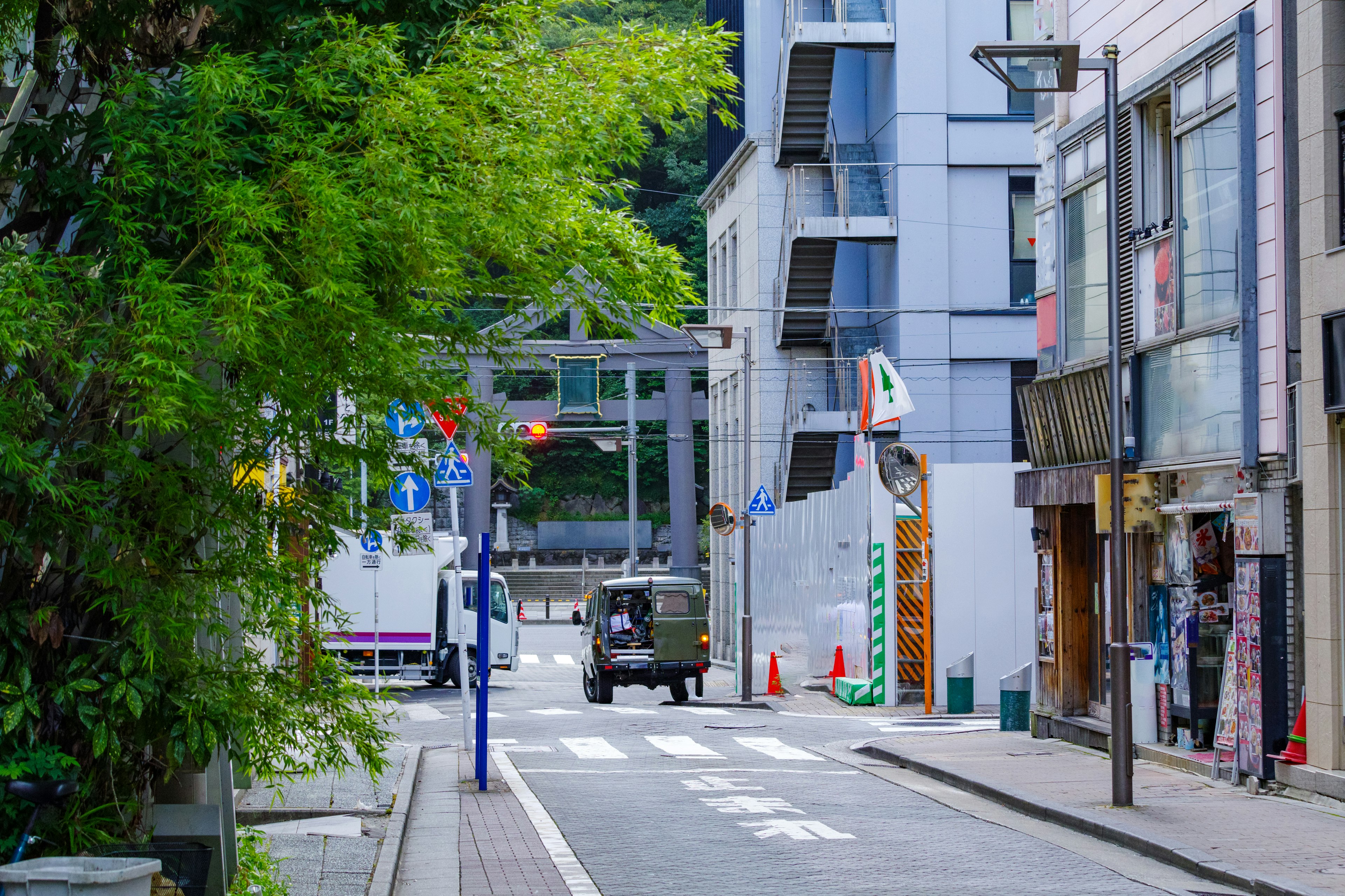 静かな街並みと緑の木々がある通りに、鳥居が見える