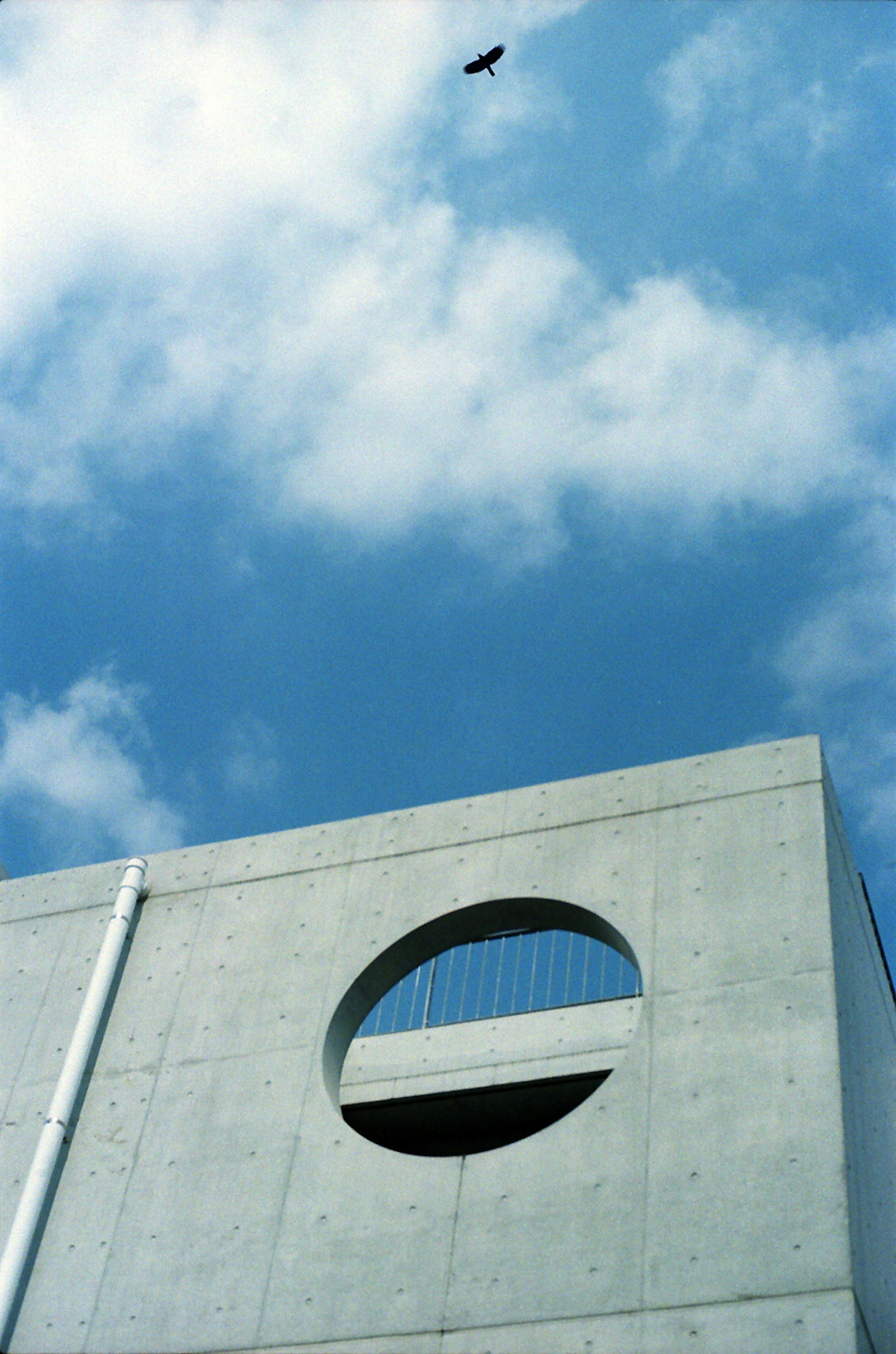 Edificio de concreto con una ventana circular bajo un cielo azul