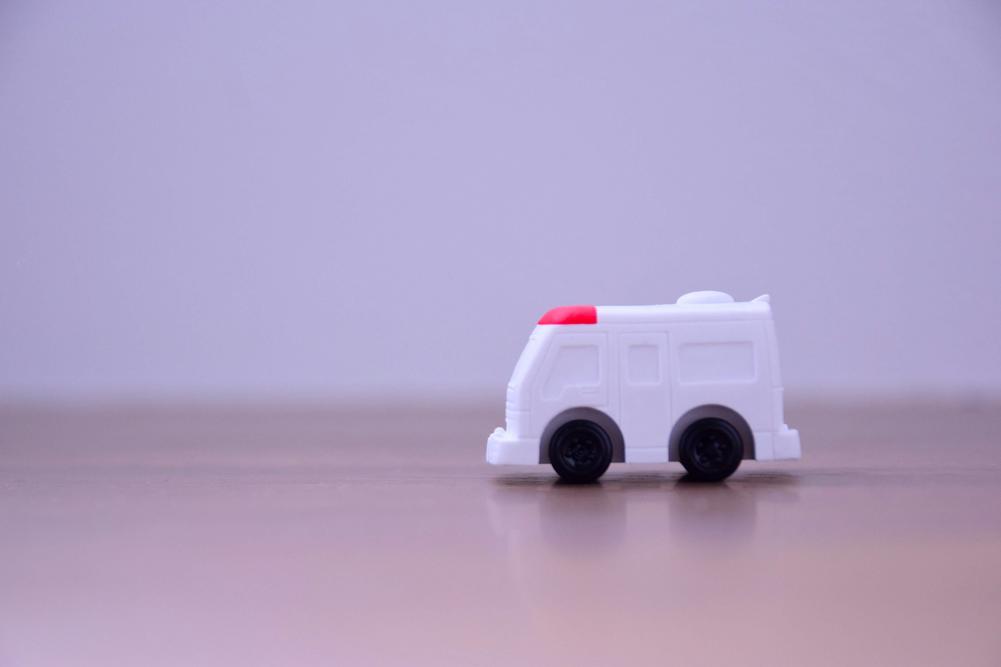 A white toy ambulance placed on a wooden table