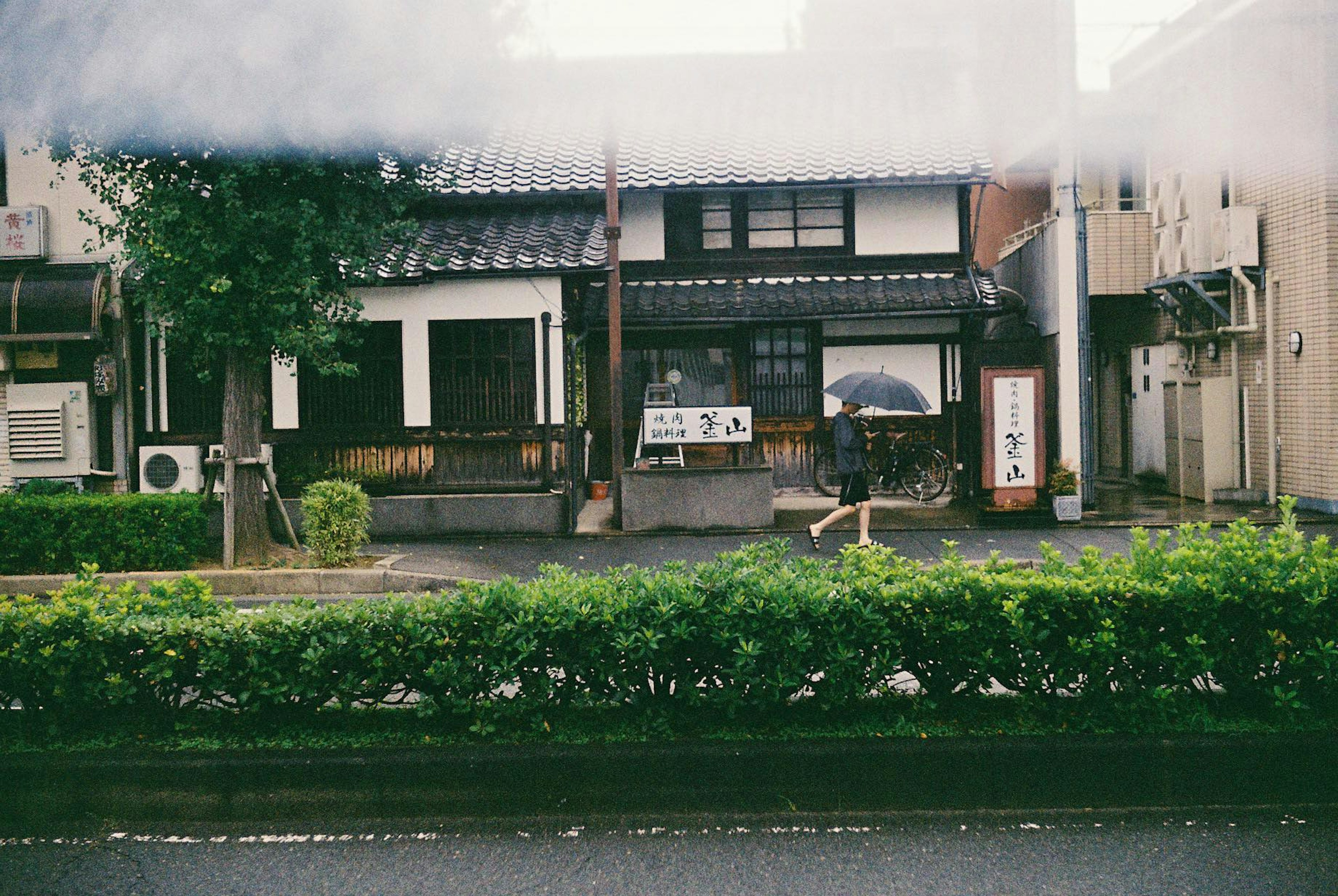 Maison japonaise traditionnelle à un coin de rue tranquille avec des haies vertes