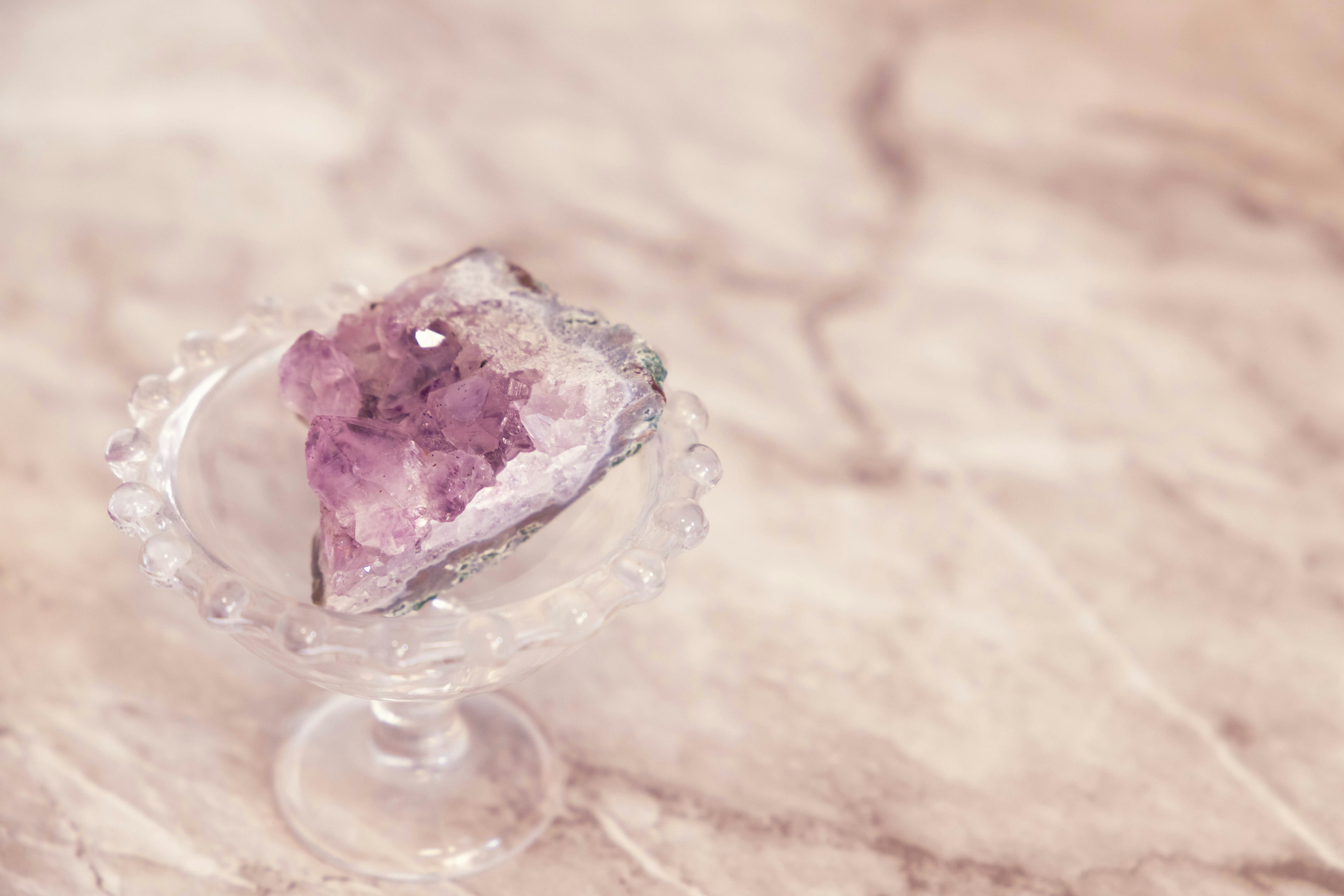 Amethyst crystal placed on a clear glass dish