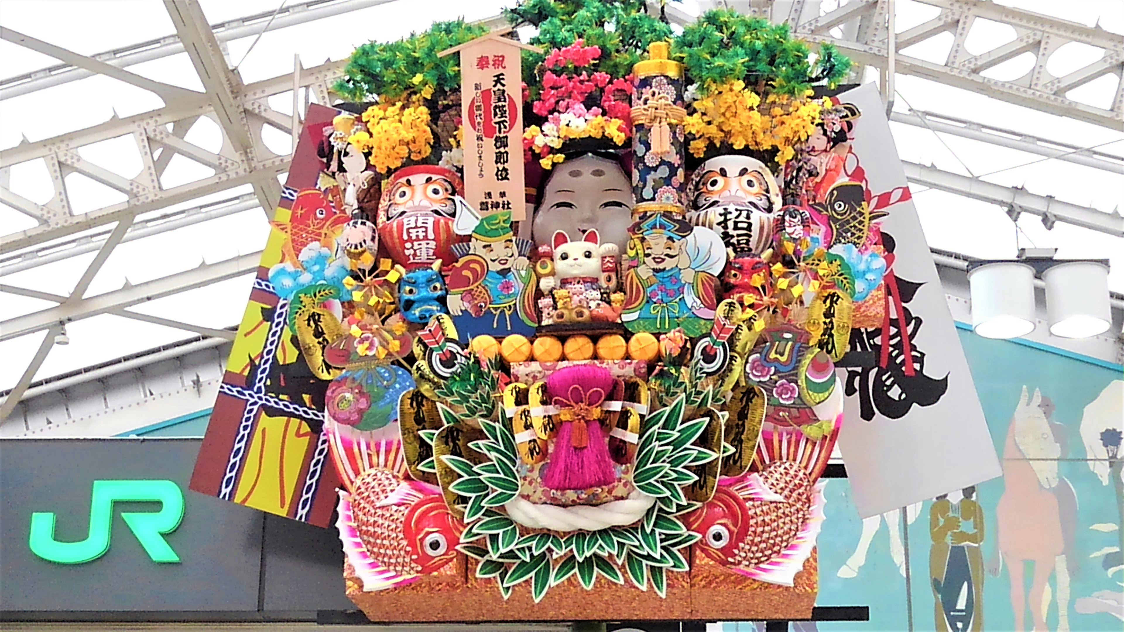 Decoraciones de festival coloridas con diversas figuras tradicionales exhibidas en una estación de tren