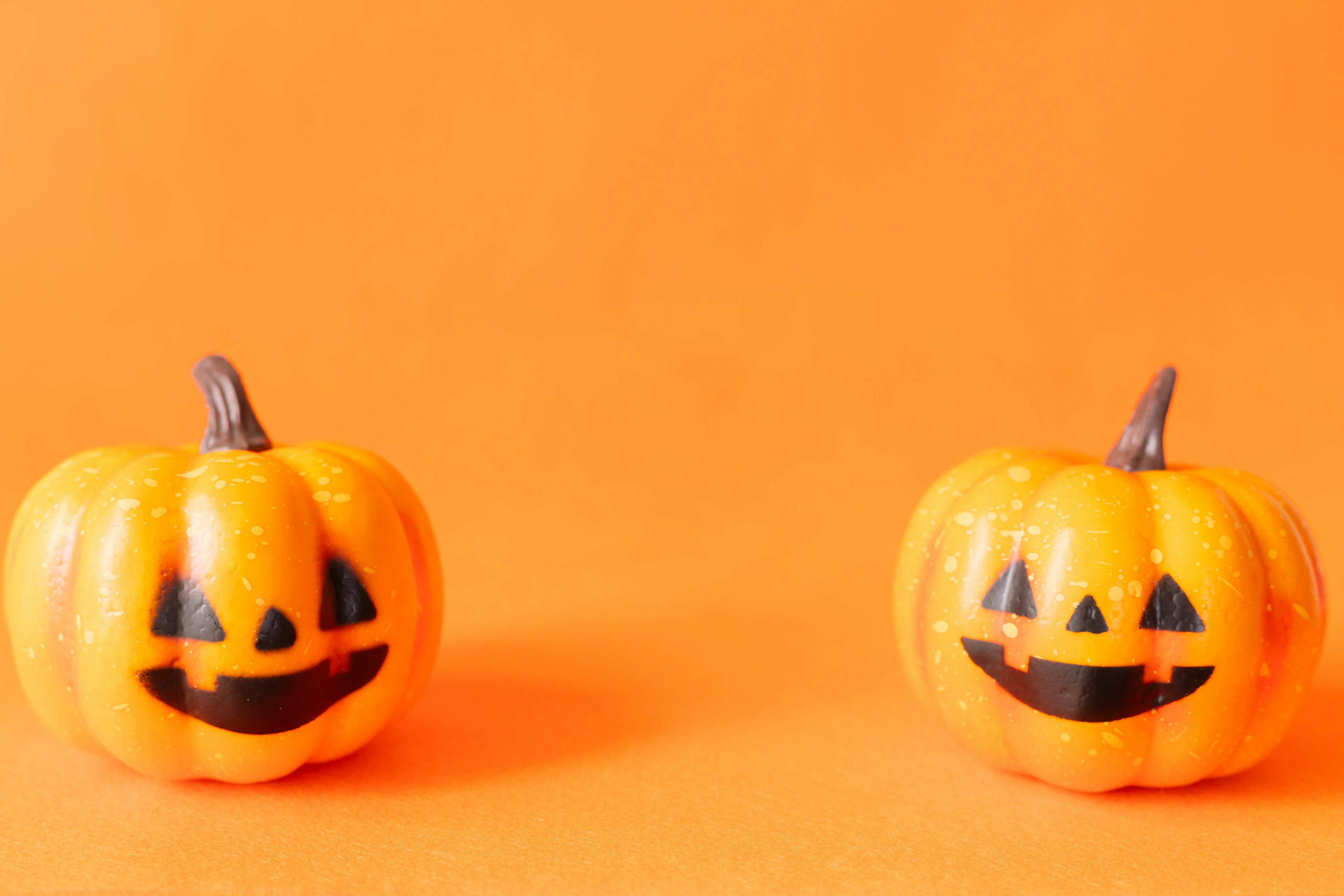 Two smiling jack-o'-lanterns on an orange background