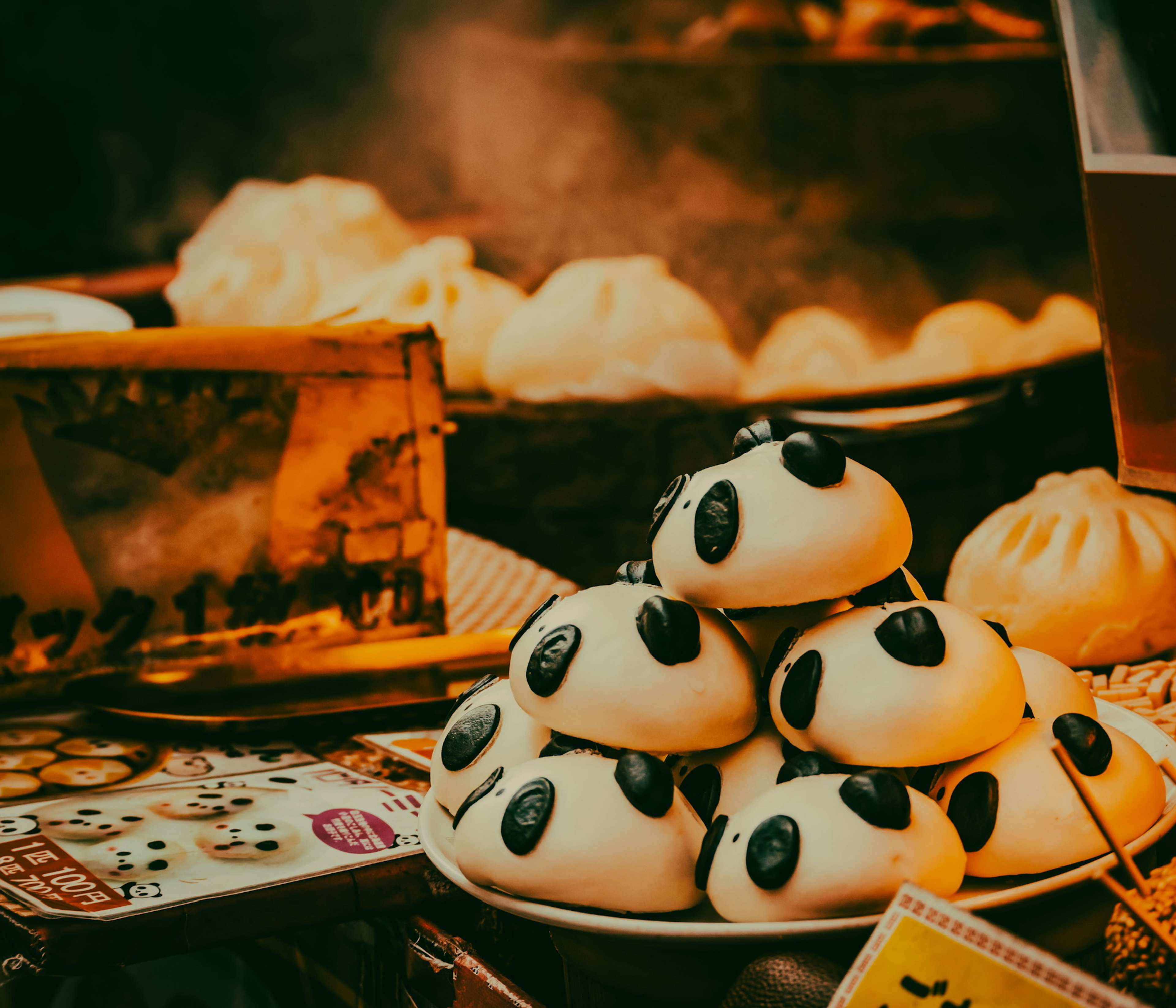 Una pila de bollos en forma de panda en un puesto de comida con vapor que se eleva