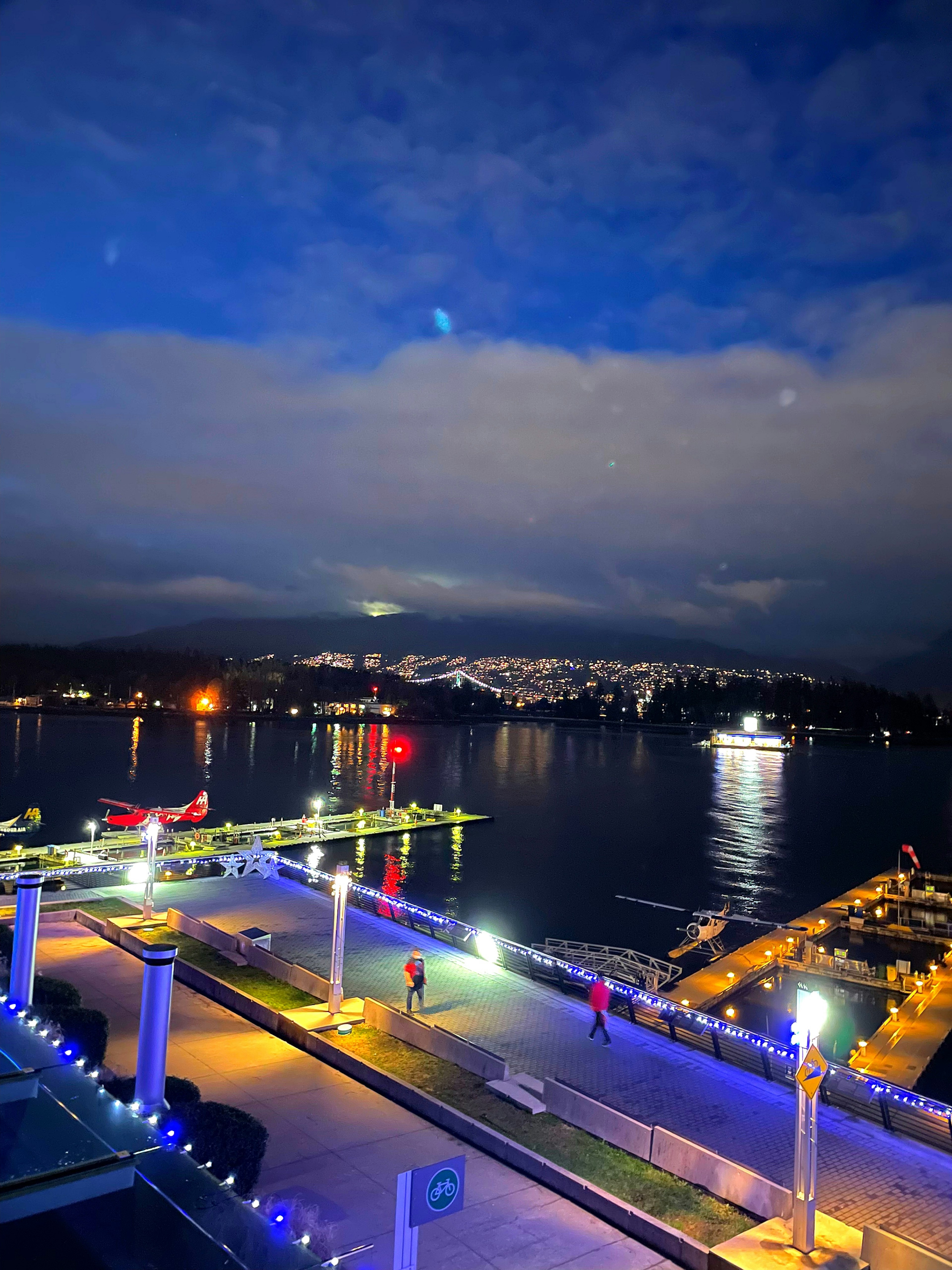 Vista nocturna de un puerto con barcos iluminados y reflejos