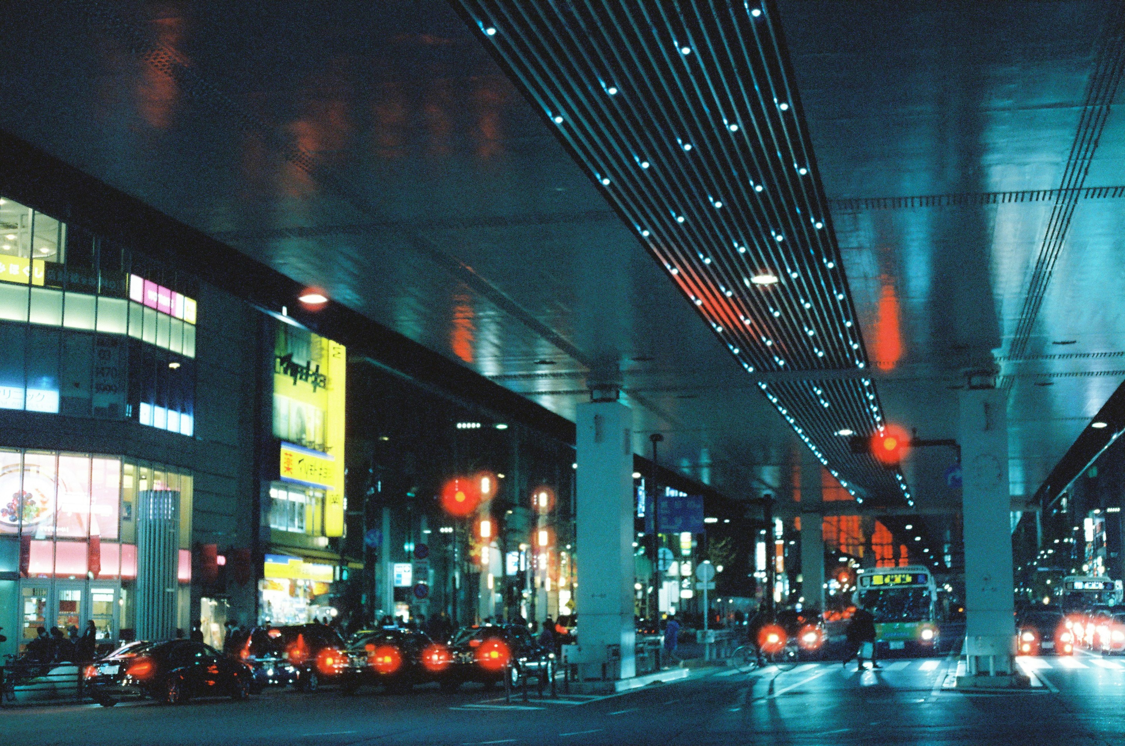 Escena nocturna urbana con un paso elevado y letreros brillantes