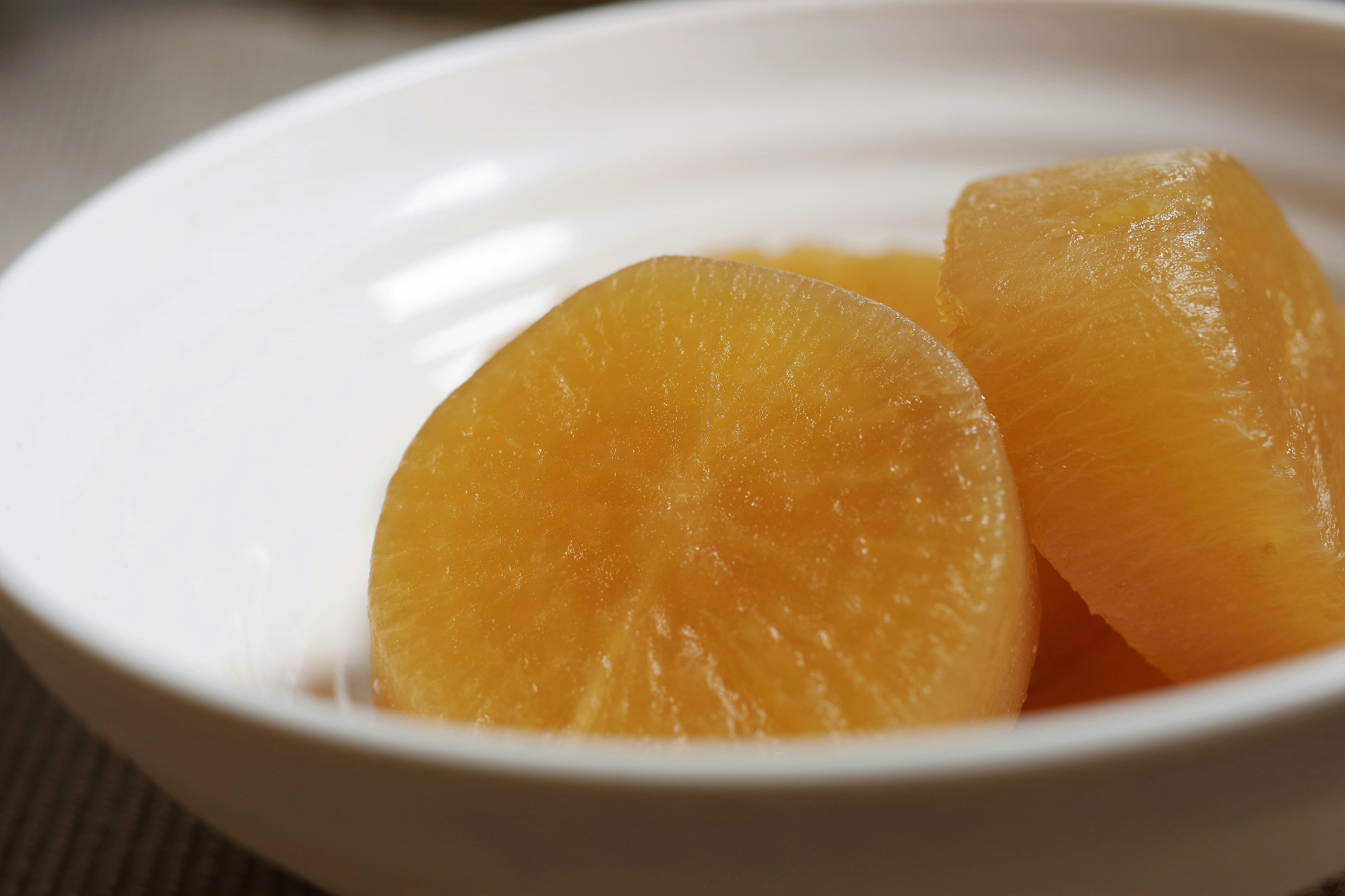 Tranches d'un radis daikon orange dans un bol blanc