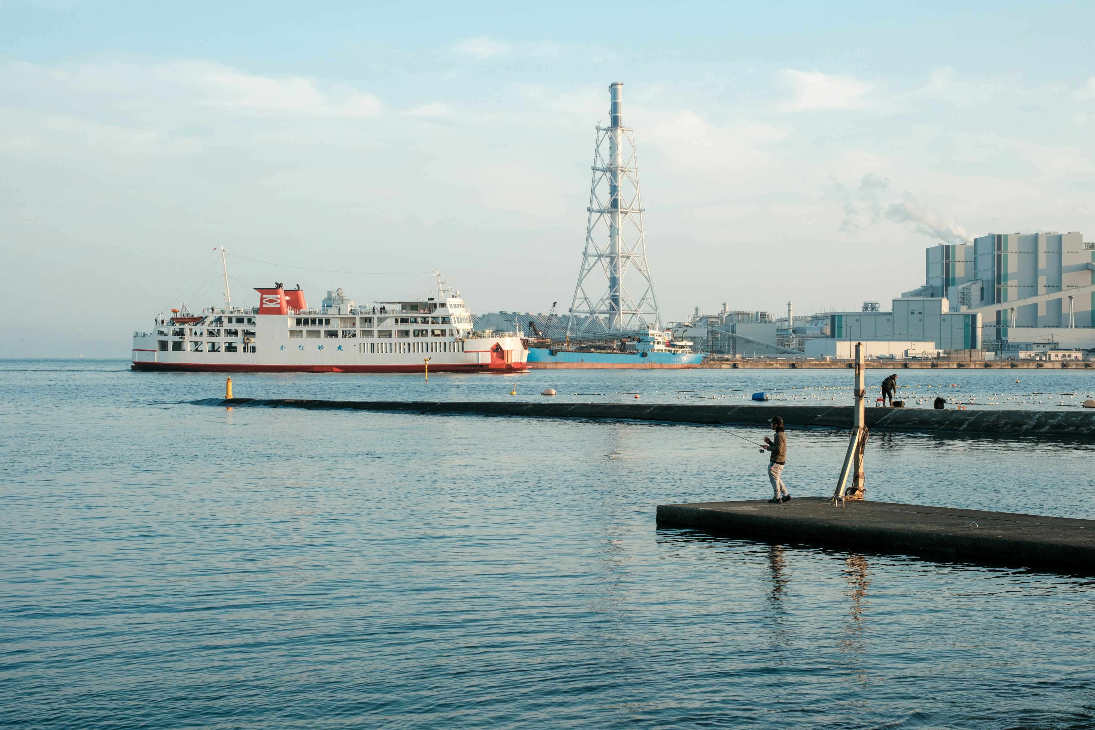 A passenger ferry on calm waters near a pier and city skyline