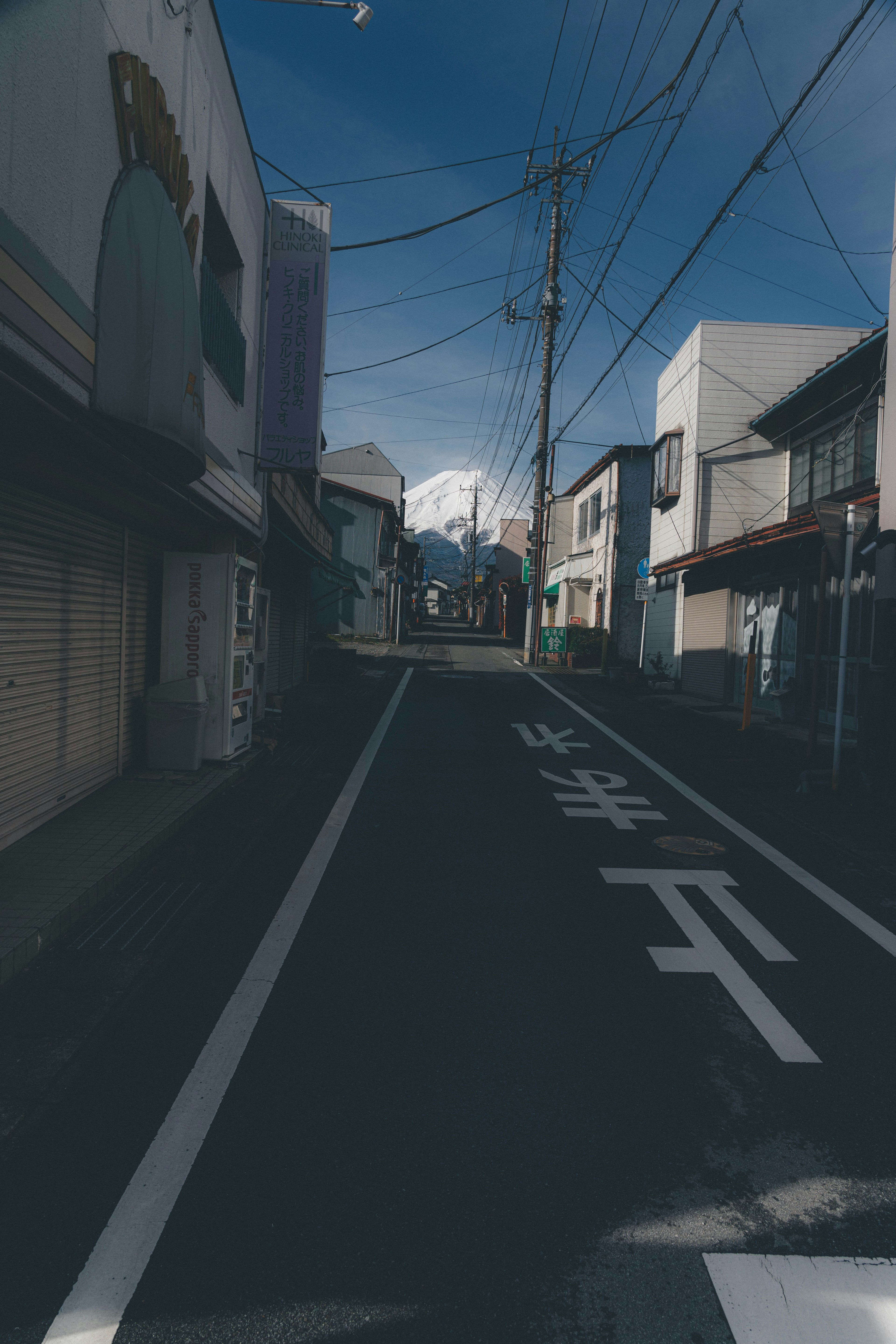 Quiet street with buildings and distant mountains under a blue sky