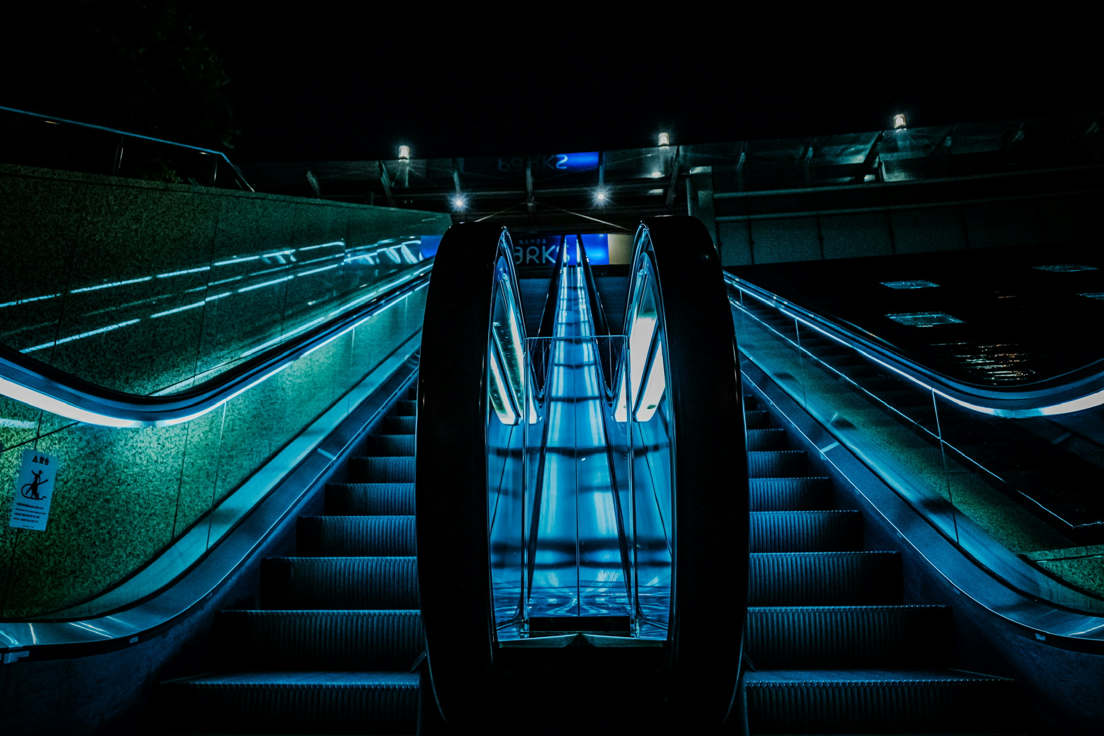 Image of an escalator illuminated by blue light in a dark space