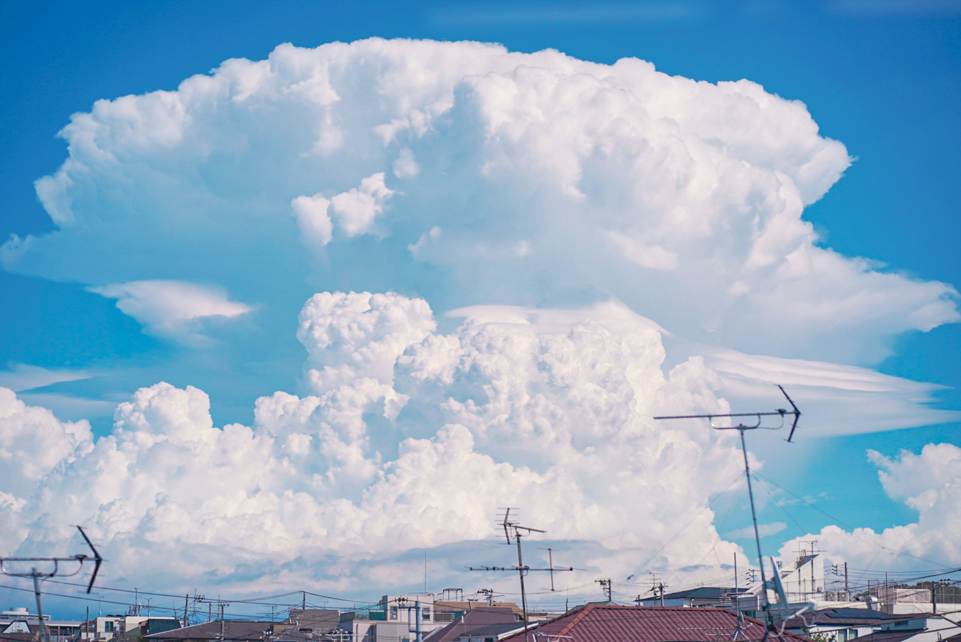 青空に浮かぶ大きな入道雲とその下の建物