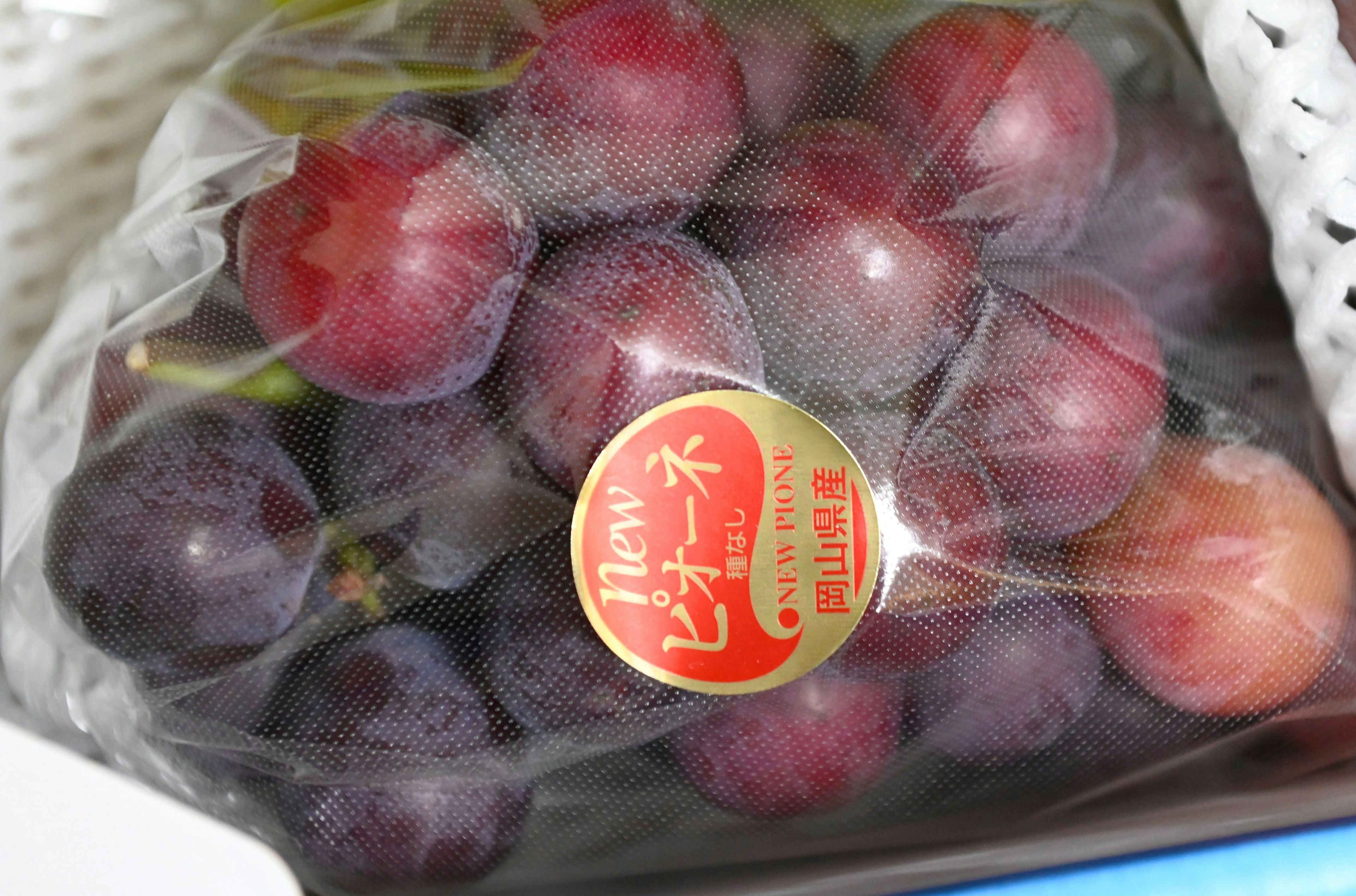 Racimo de uvas frescas en una bolsa transparente con variedades rojas y moradas