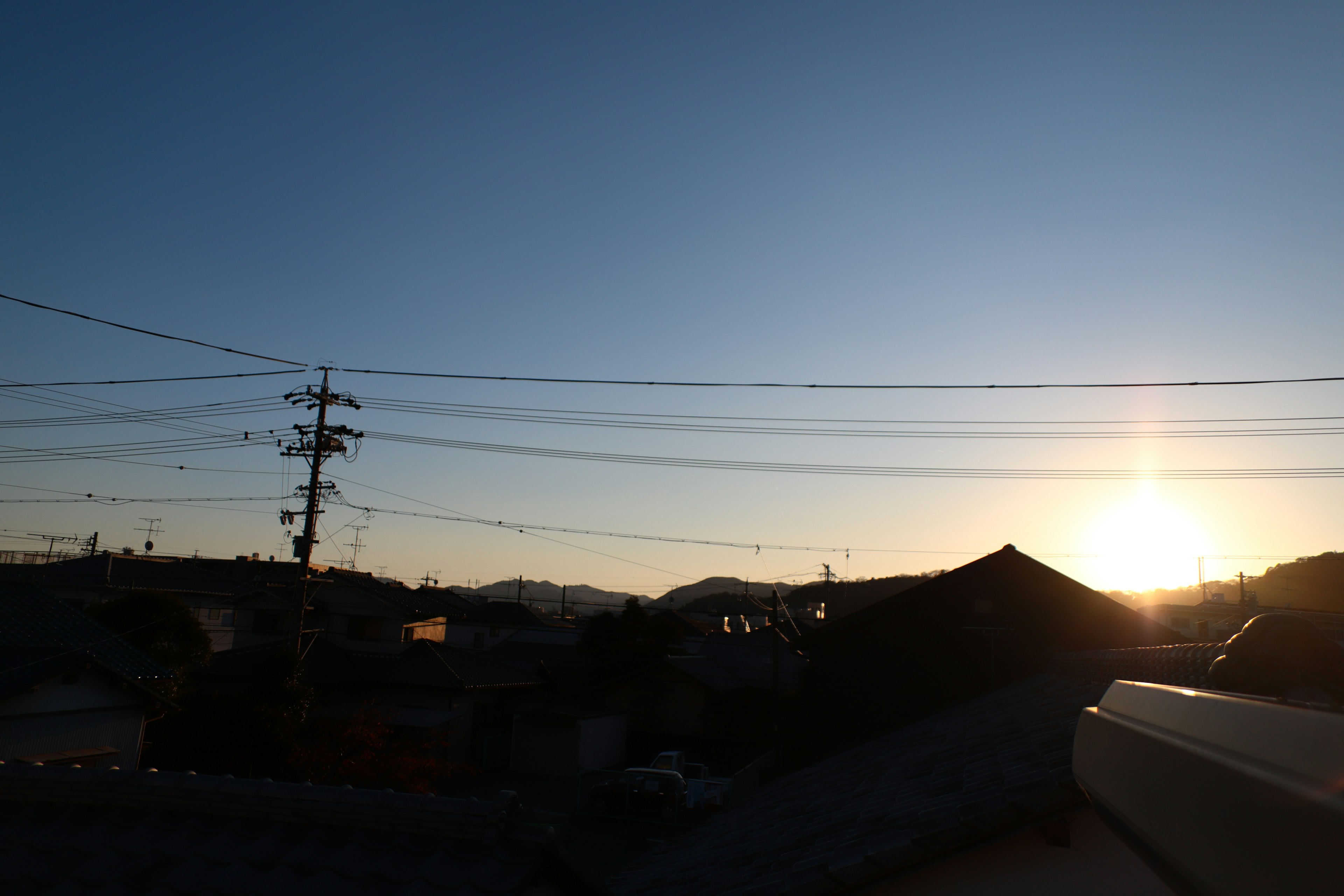 Sonnenuntergang über einem japanischen Wohngebiet mit Stromleitungen