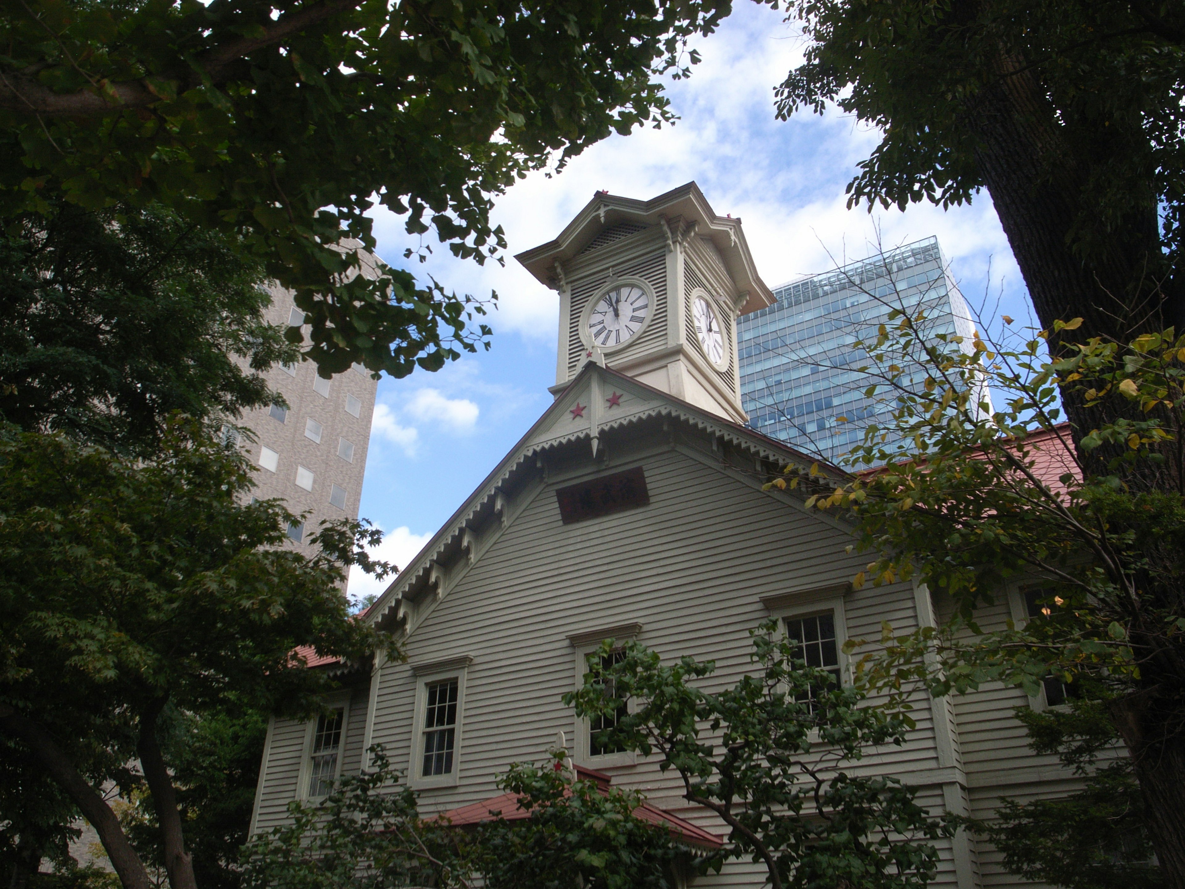 時計塔のある古い木造建築と近代的なビルが背景の風景