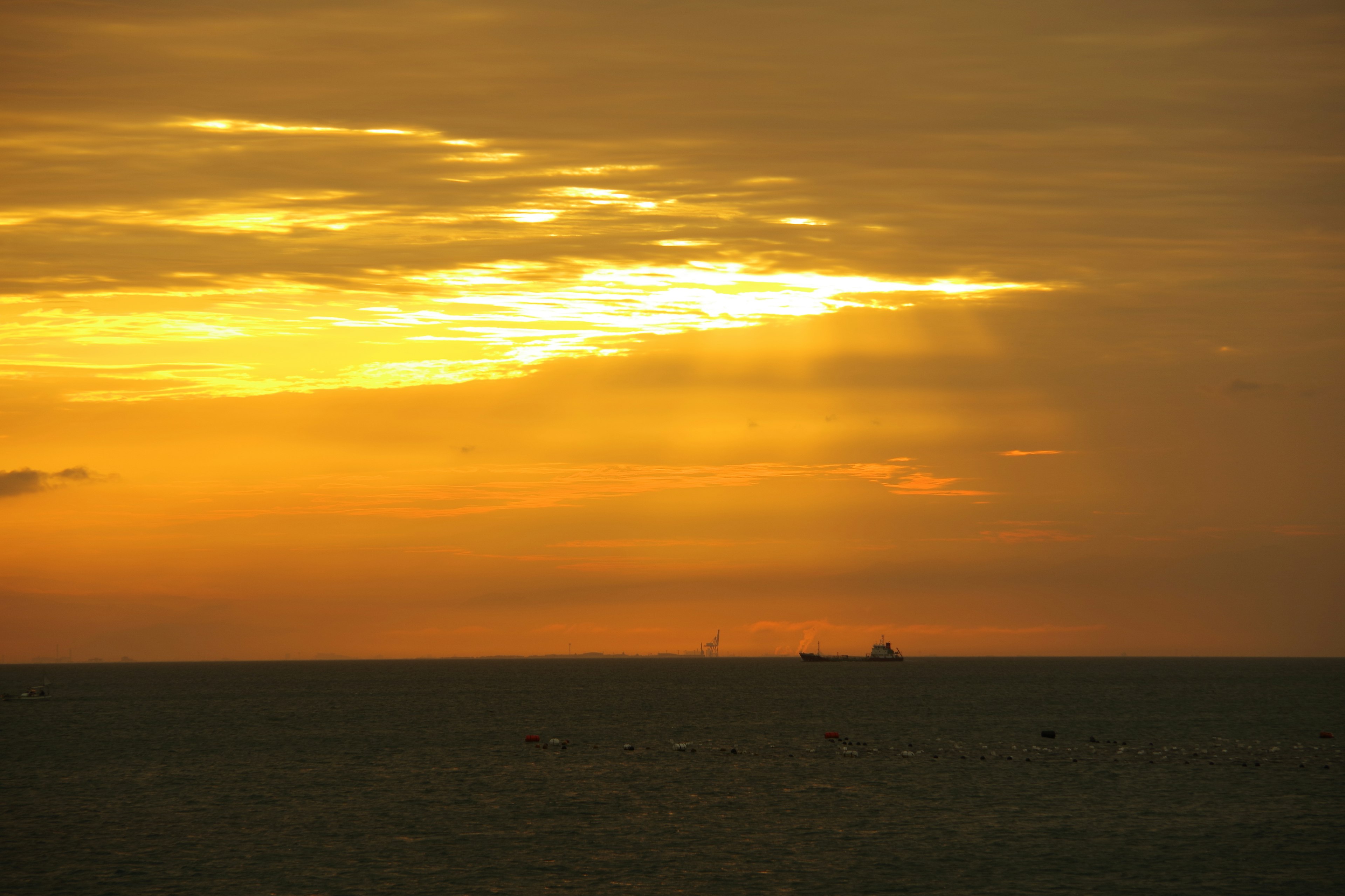 夕焼けの海の風景　オレンジと黄色の空　遠くに船