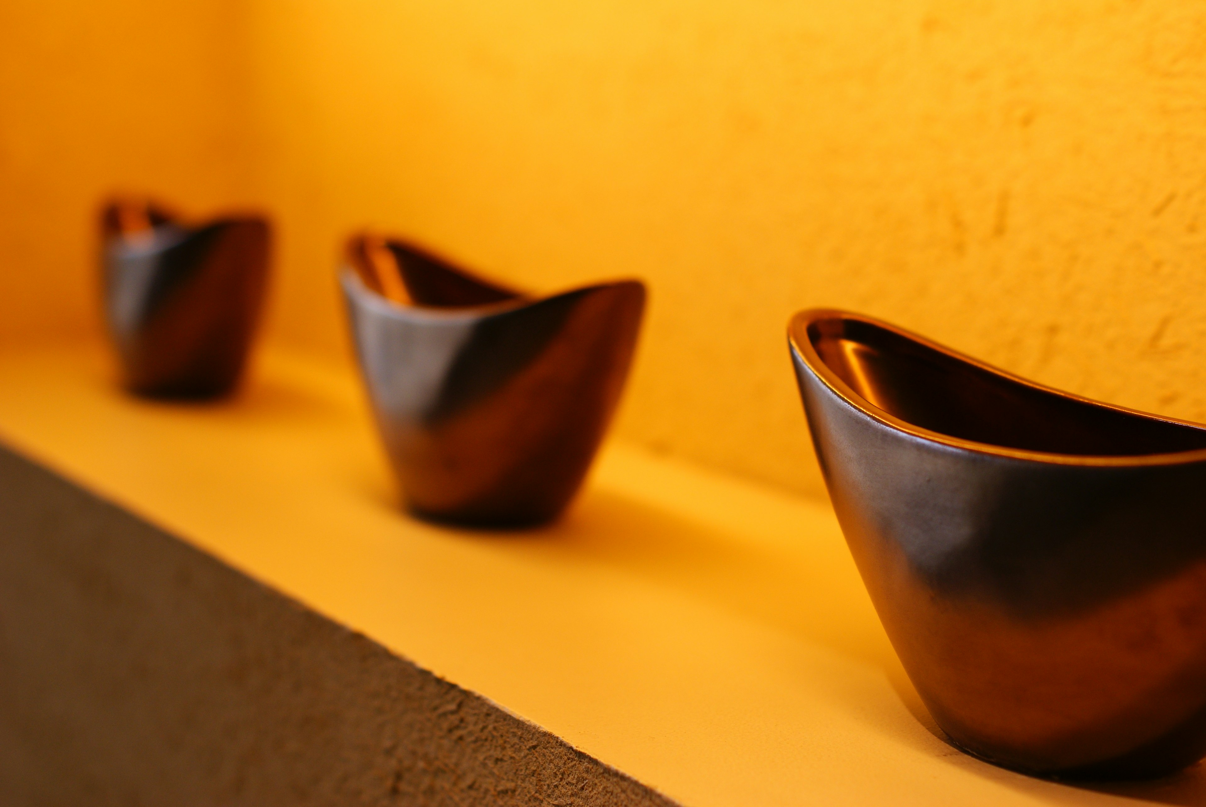 Three elegant ceramic bowls arranged against a warm-toned background