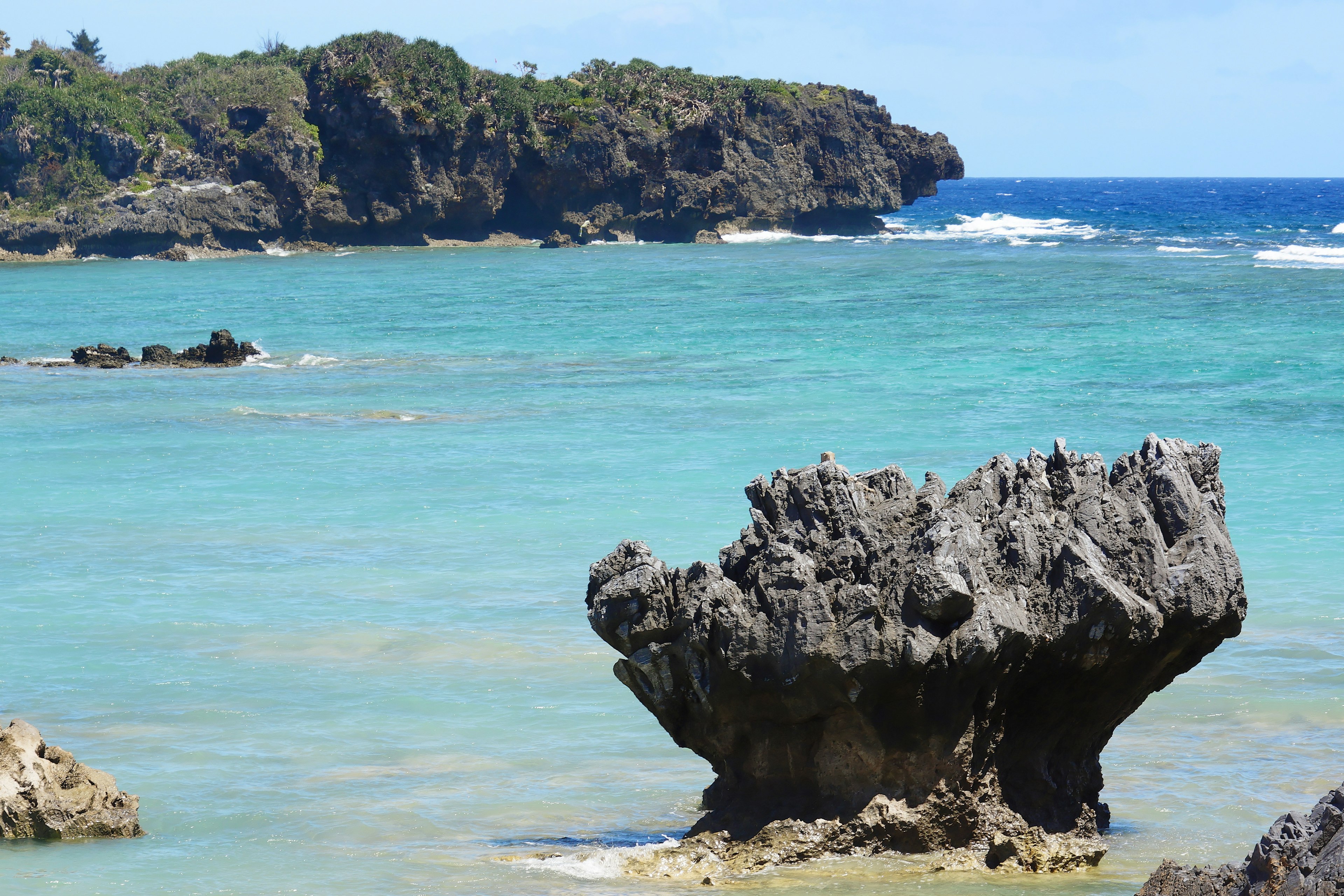 Pemandangan laut turquoise dengan formasi batu dan vegetasi subur