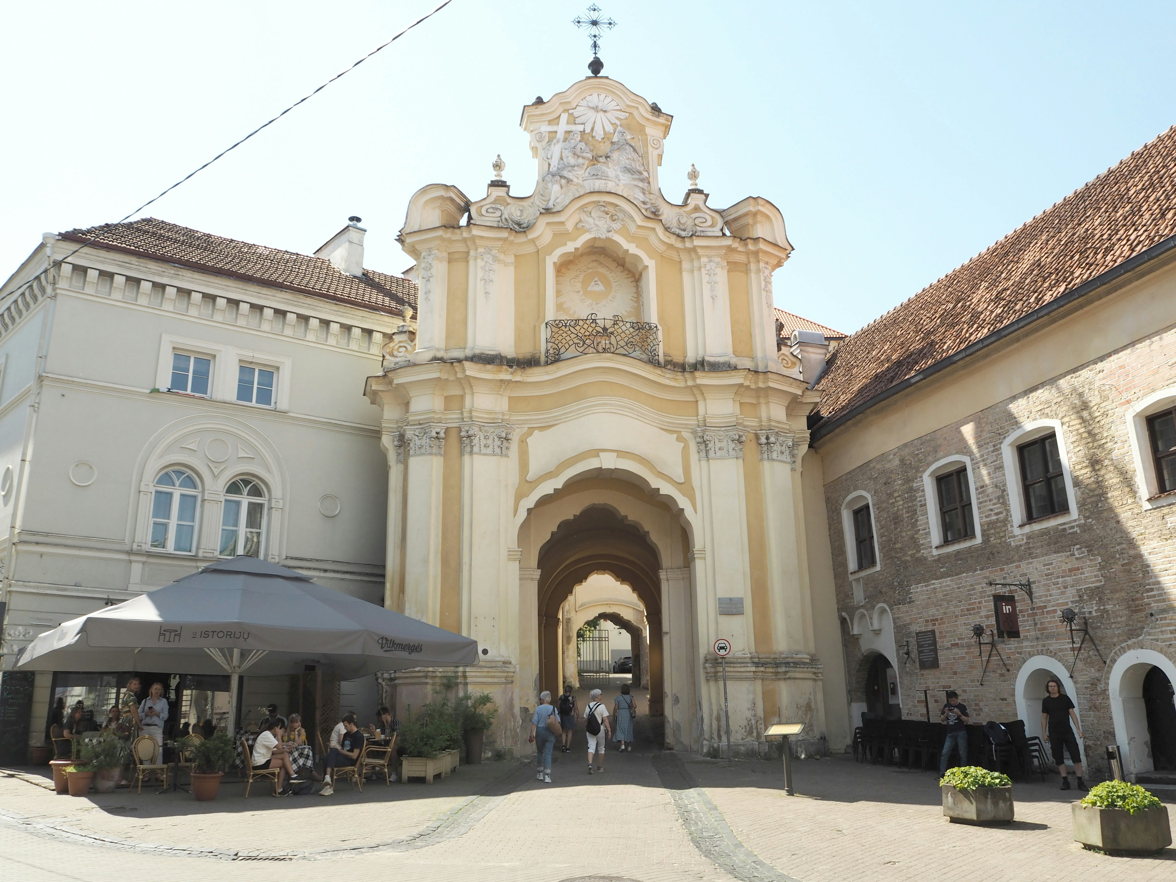 Bâtiment historique avec une arche et un café en plein air dans une place