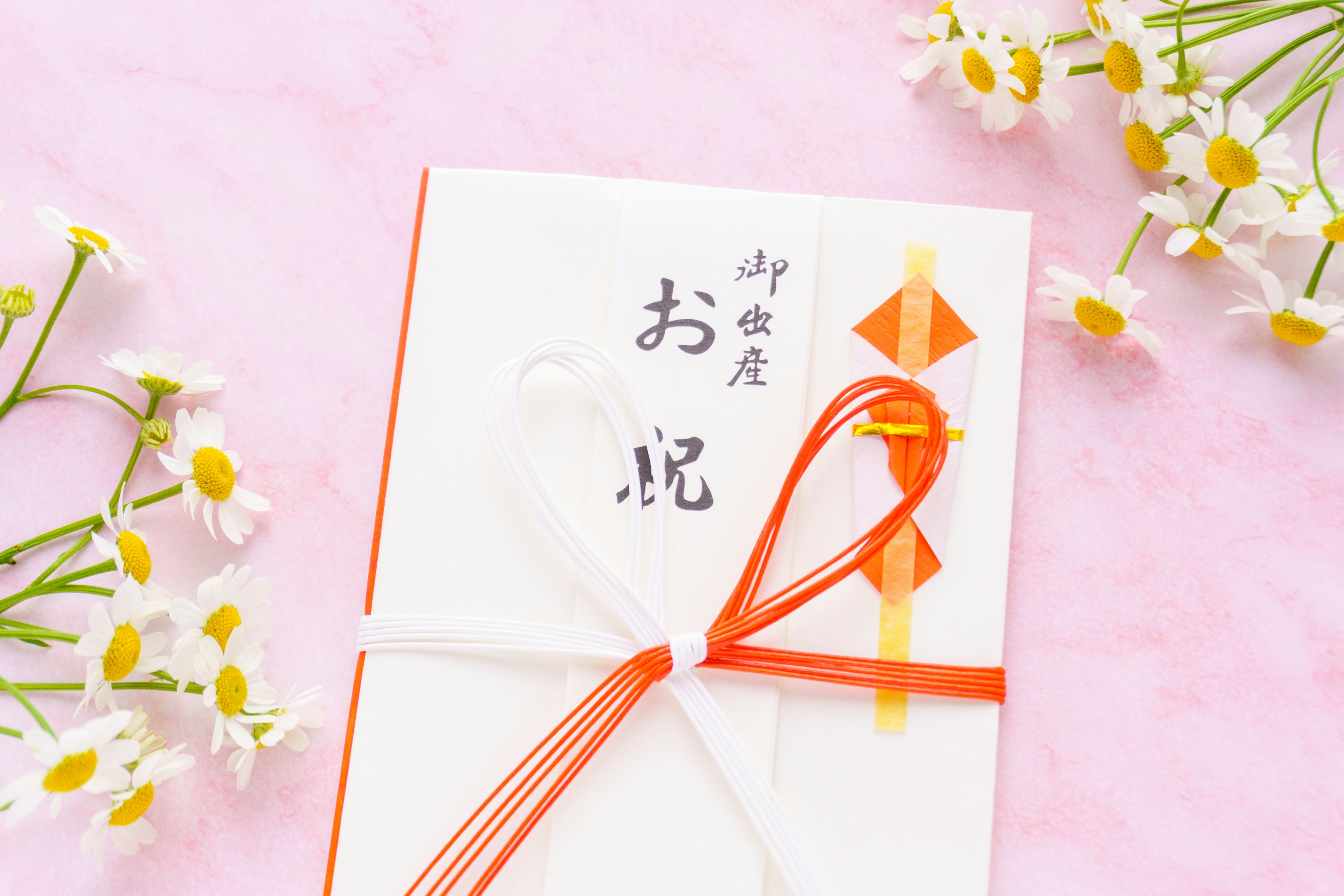 A white envelope tied with red and white ribbons featuring a celebration card surrounded by small flowers