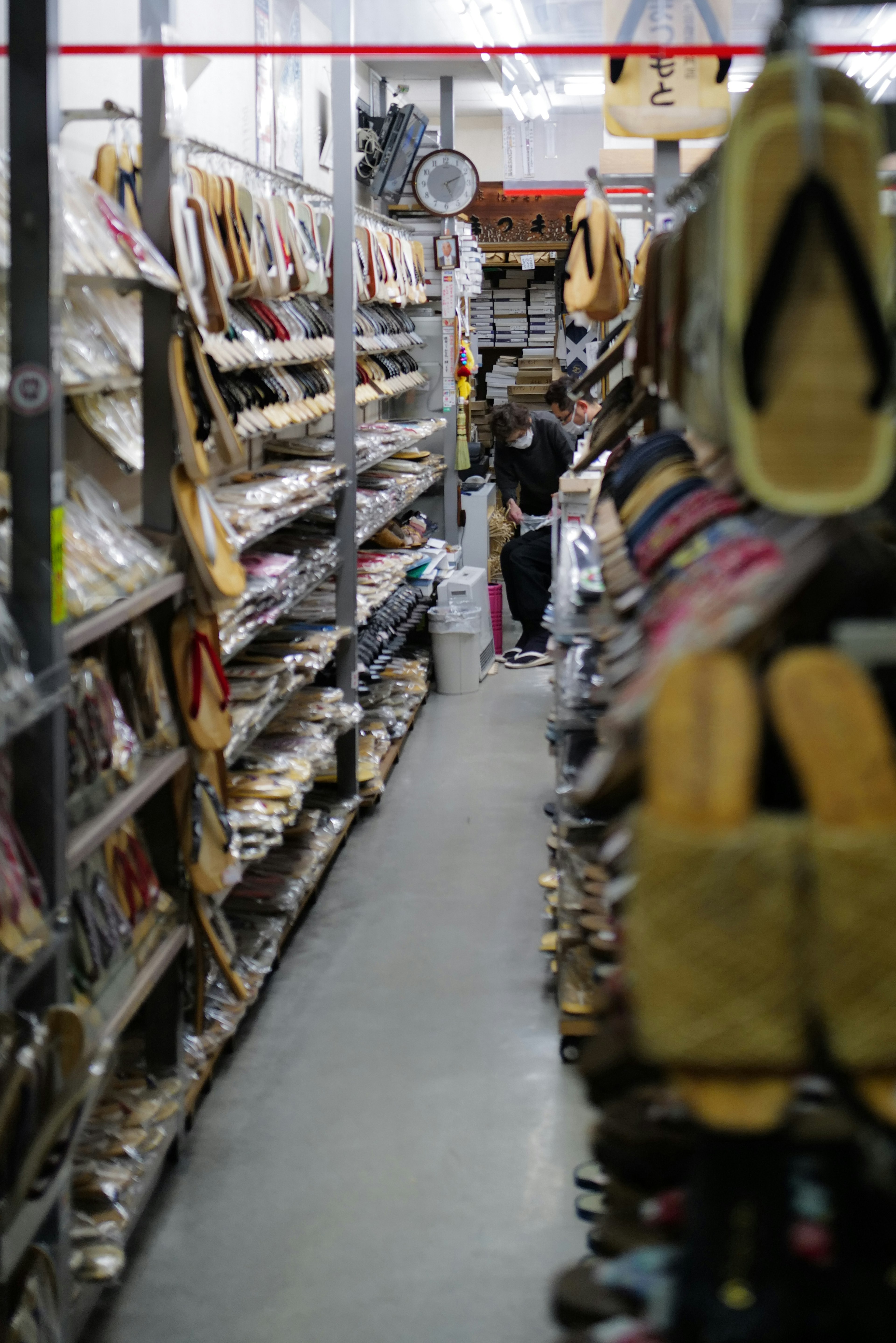 Interior of a shoe store with various shoes displayed on shelves and a customer