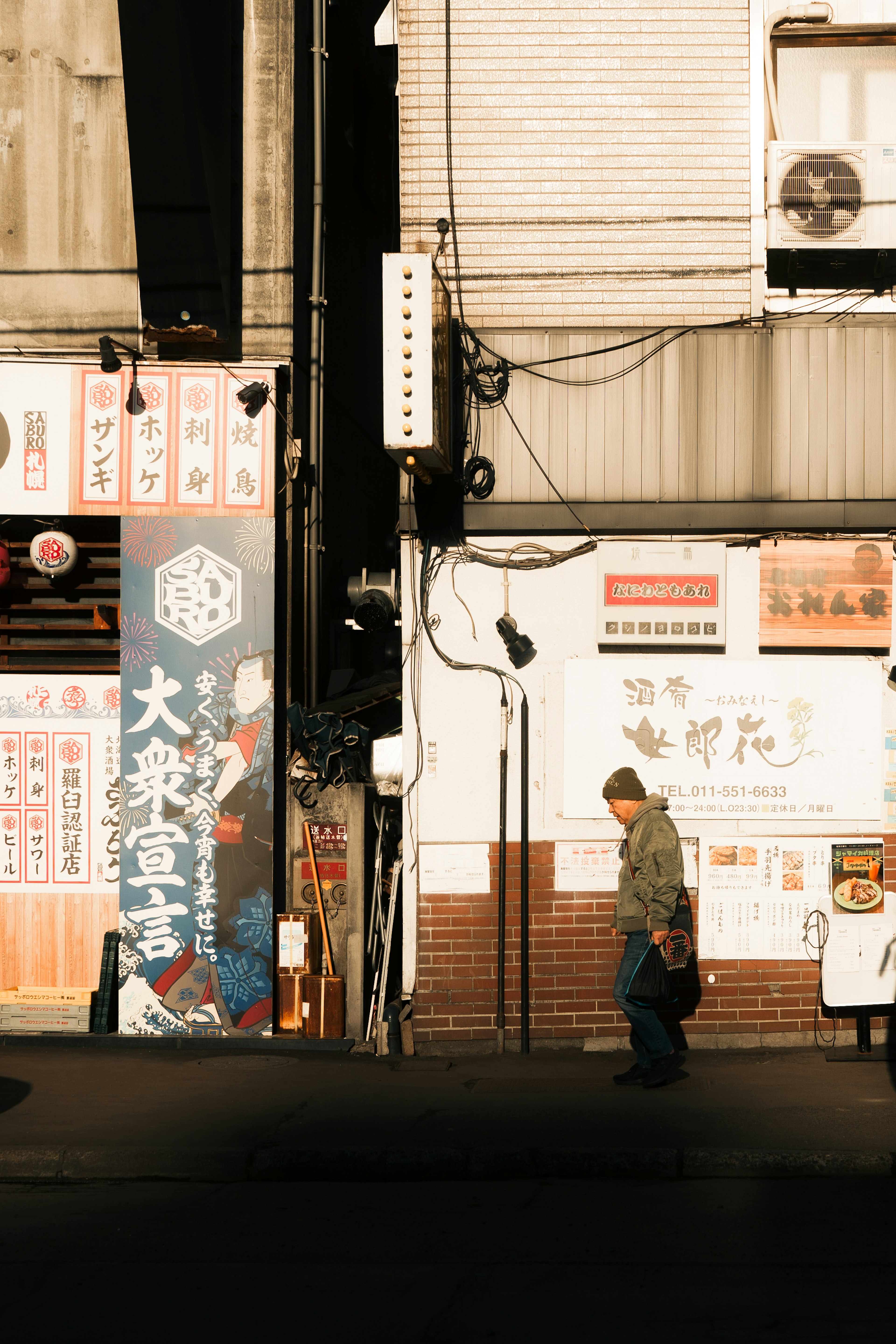 一个人在城市巷子里走，周围有色彩鲜艳的标志