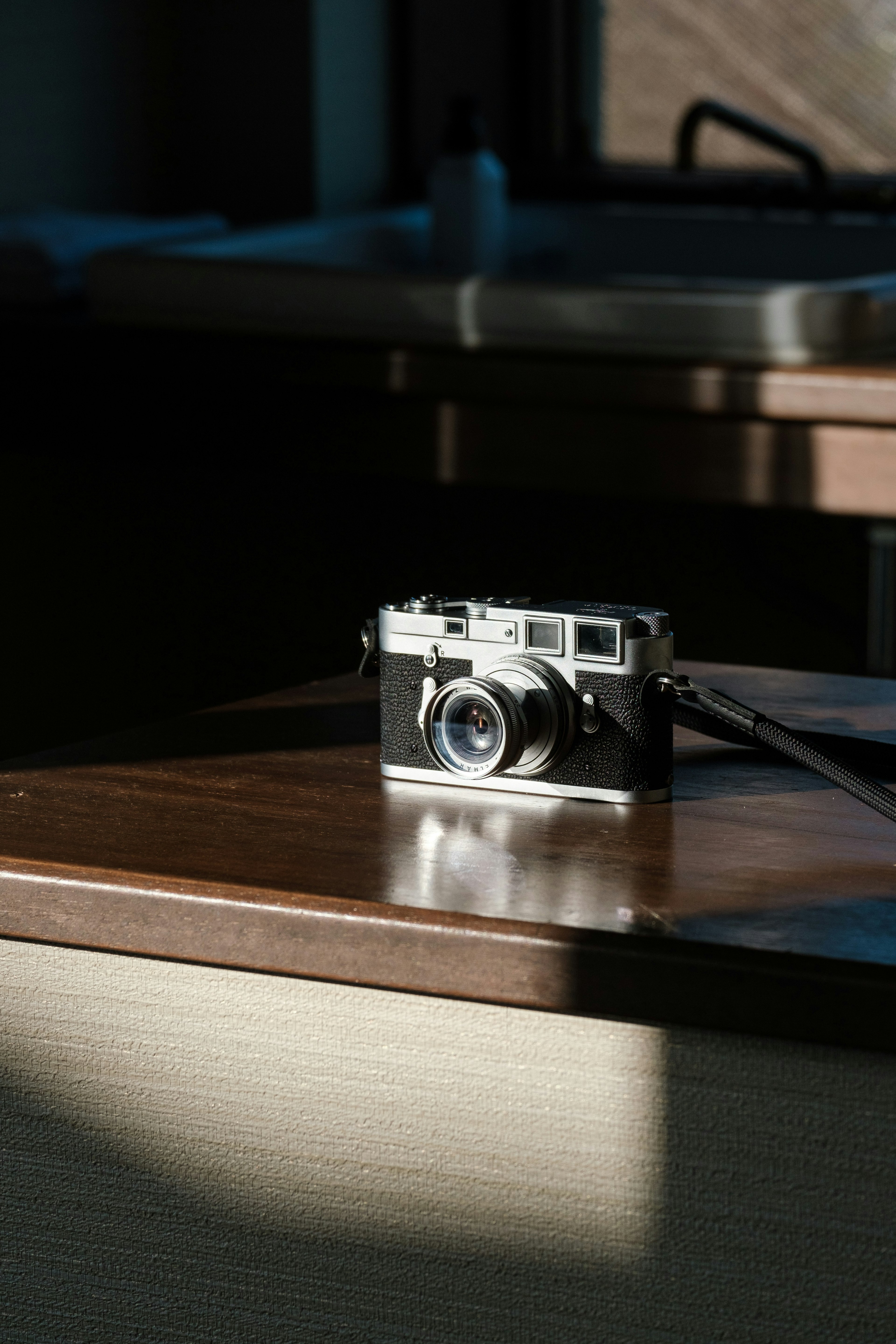 Appareil photo classique posé sur une table en bois éclairée par la lumière naturelle