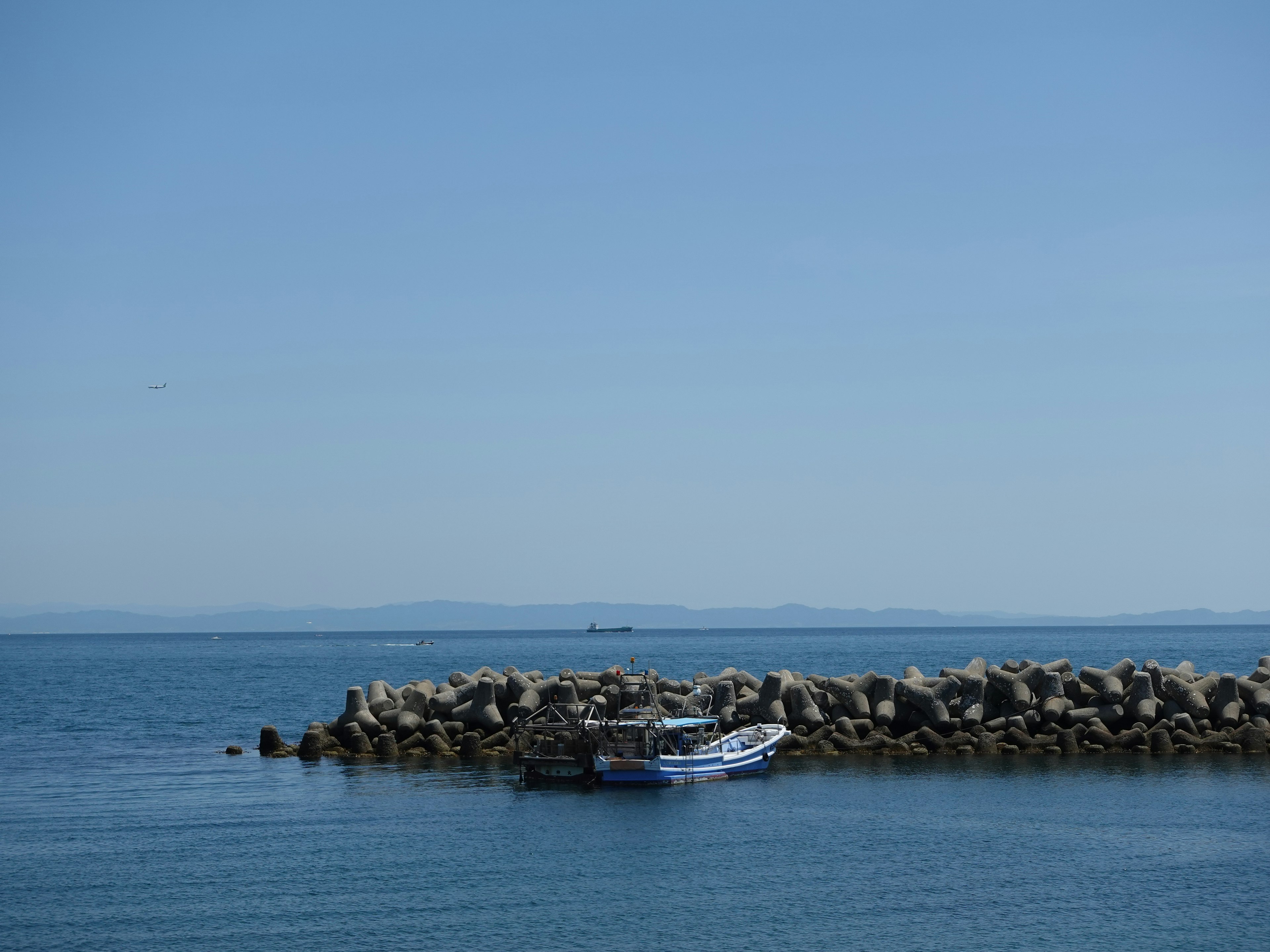 A small boat docked at a rocky shore with a clear blue sky