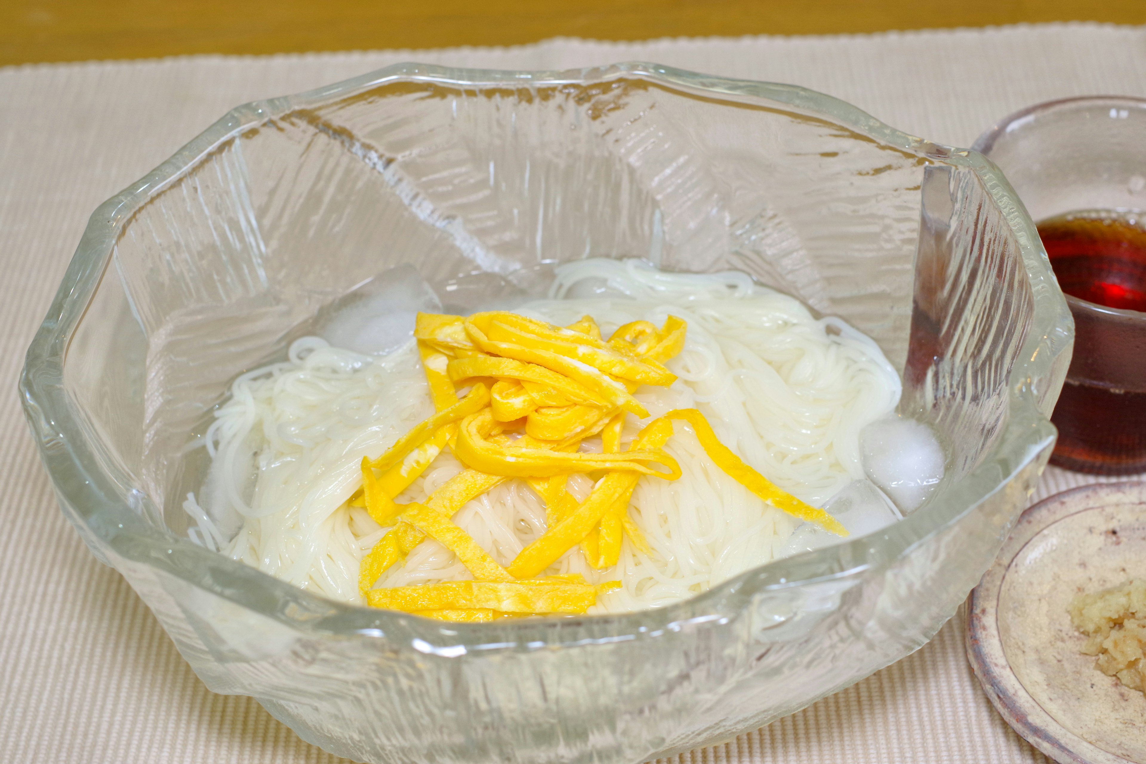 Cold noodles served in a glass bowl topped with shredded egg