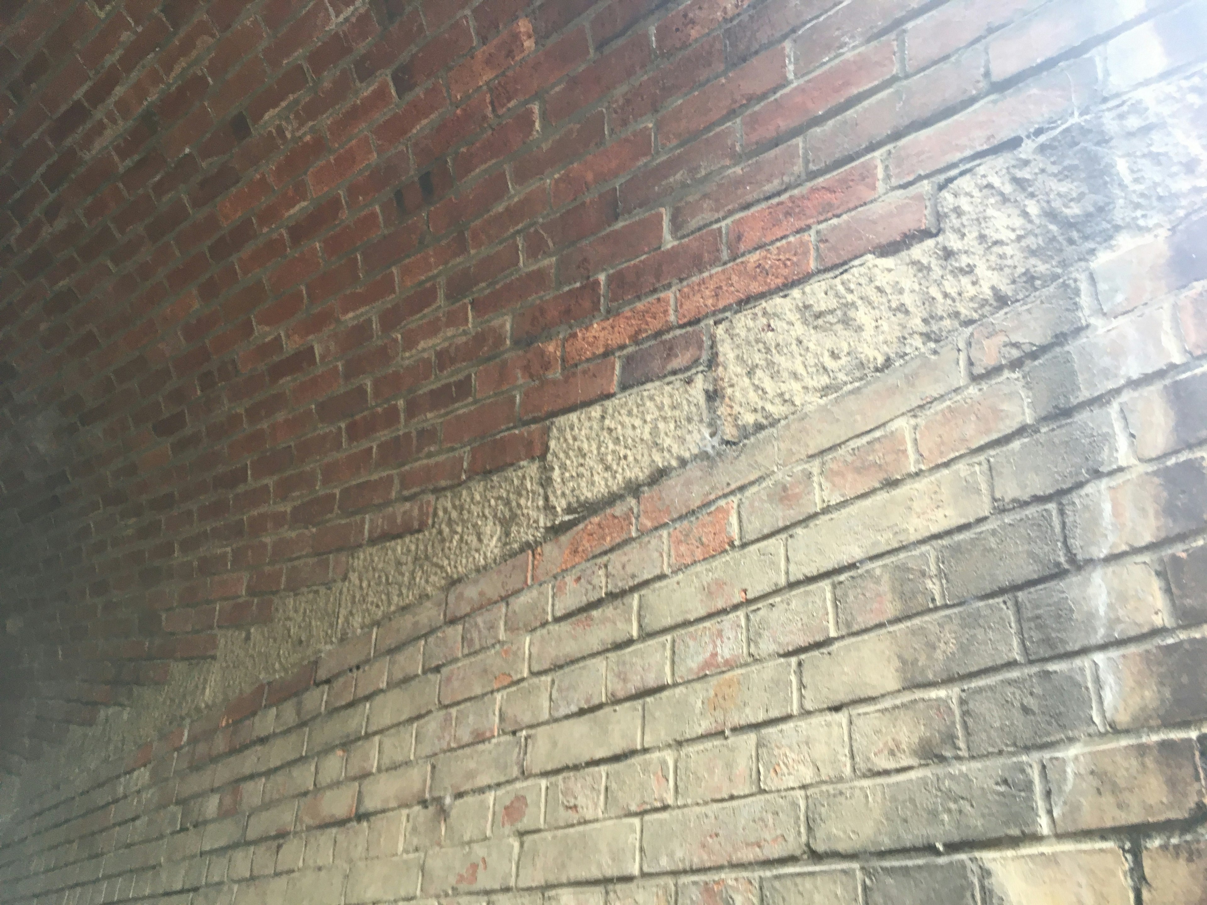 Section of a red brick wall showing distinct texture variations