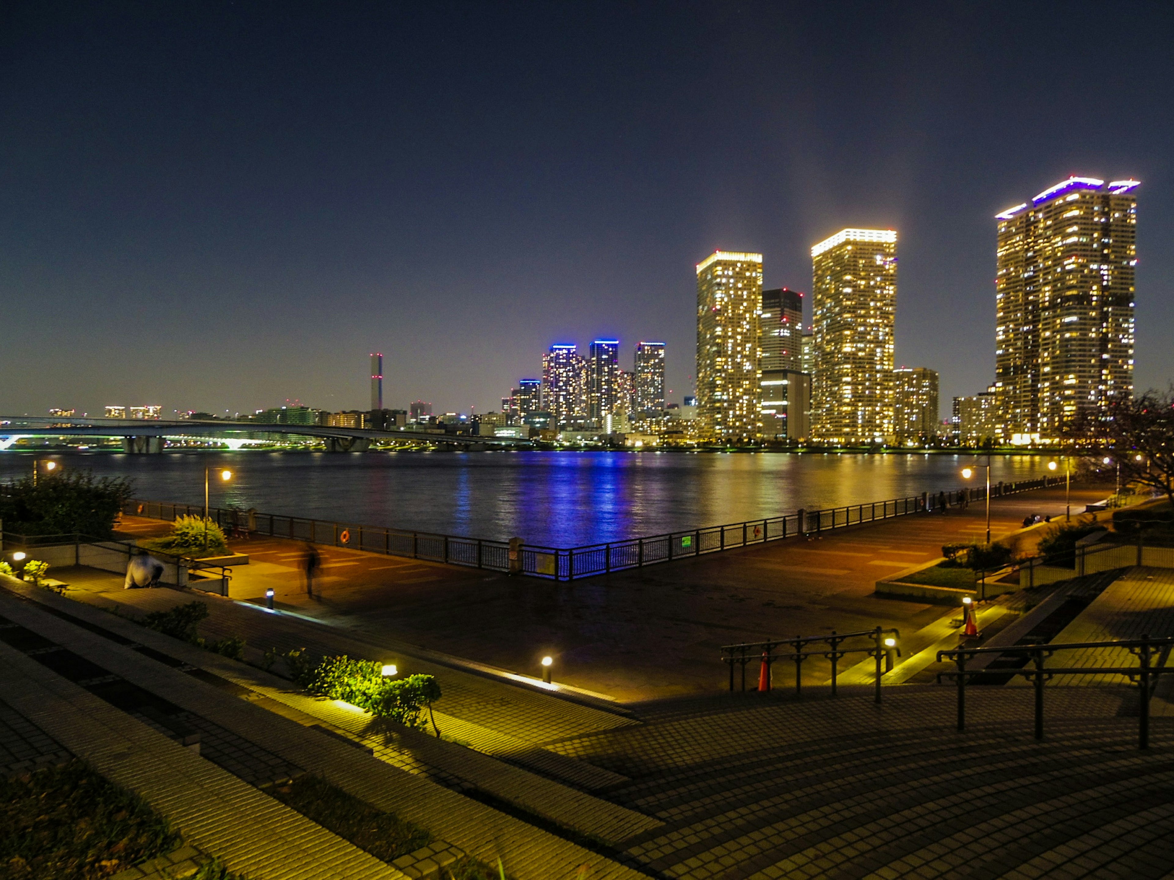 Hermoso paisaje urbano con rascacielos y reflejos en el agua por la noche