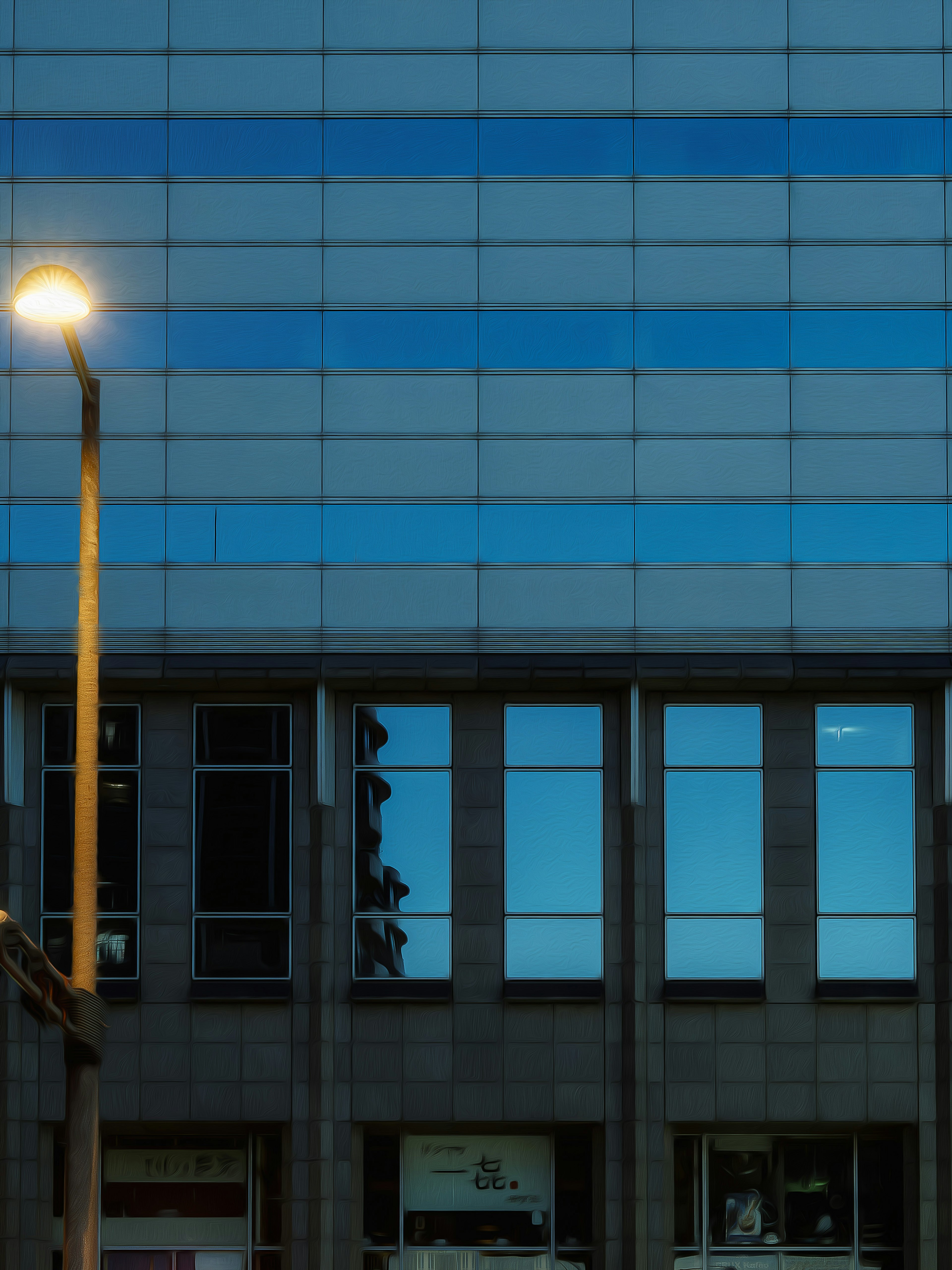 Fassade eines blauen Glasgebäudes mit Straßenlaternenreflexion