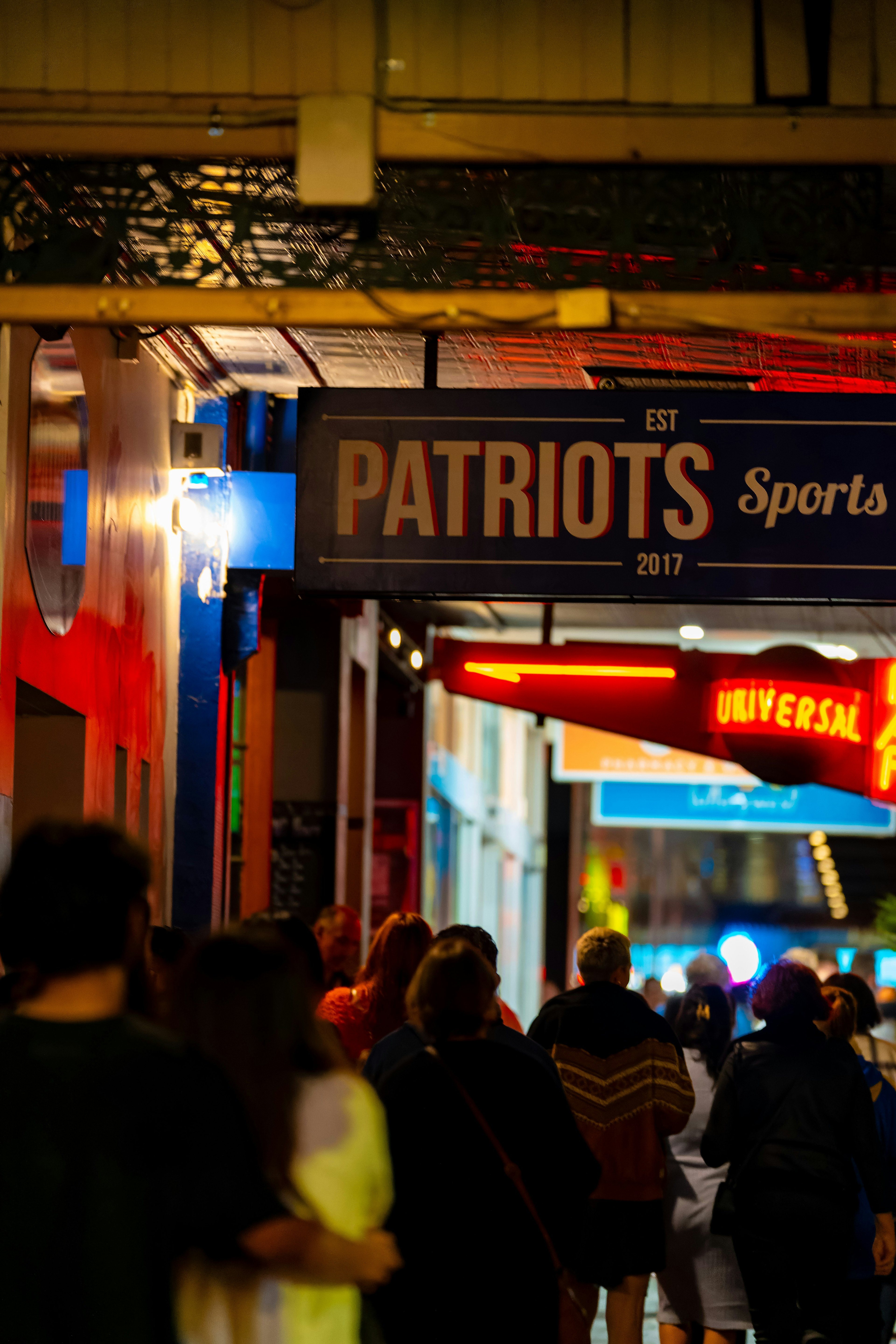 Belebte Straßenszene mit dem Schild Patriots Sports