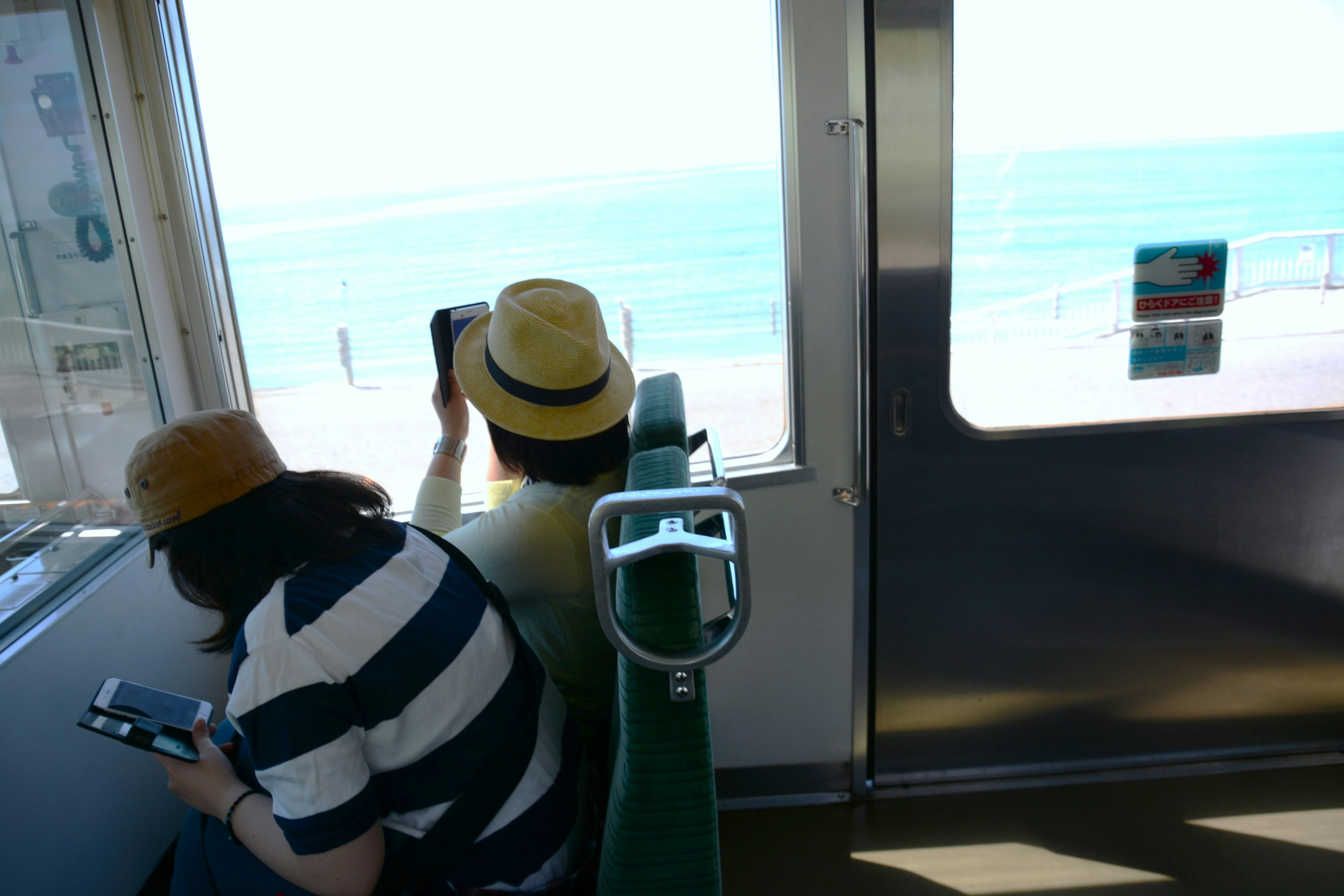 Two passengers in a train car looking at the ocean