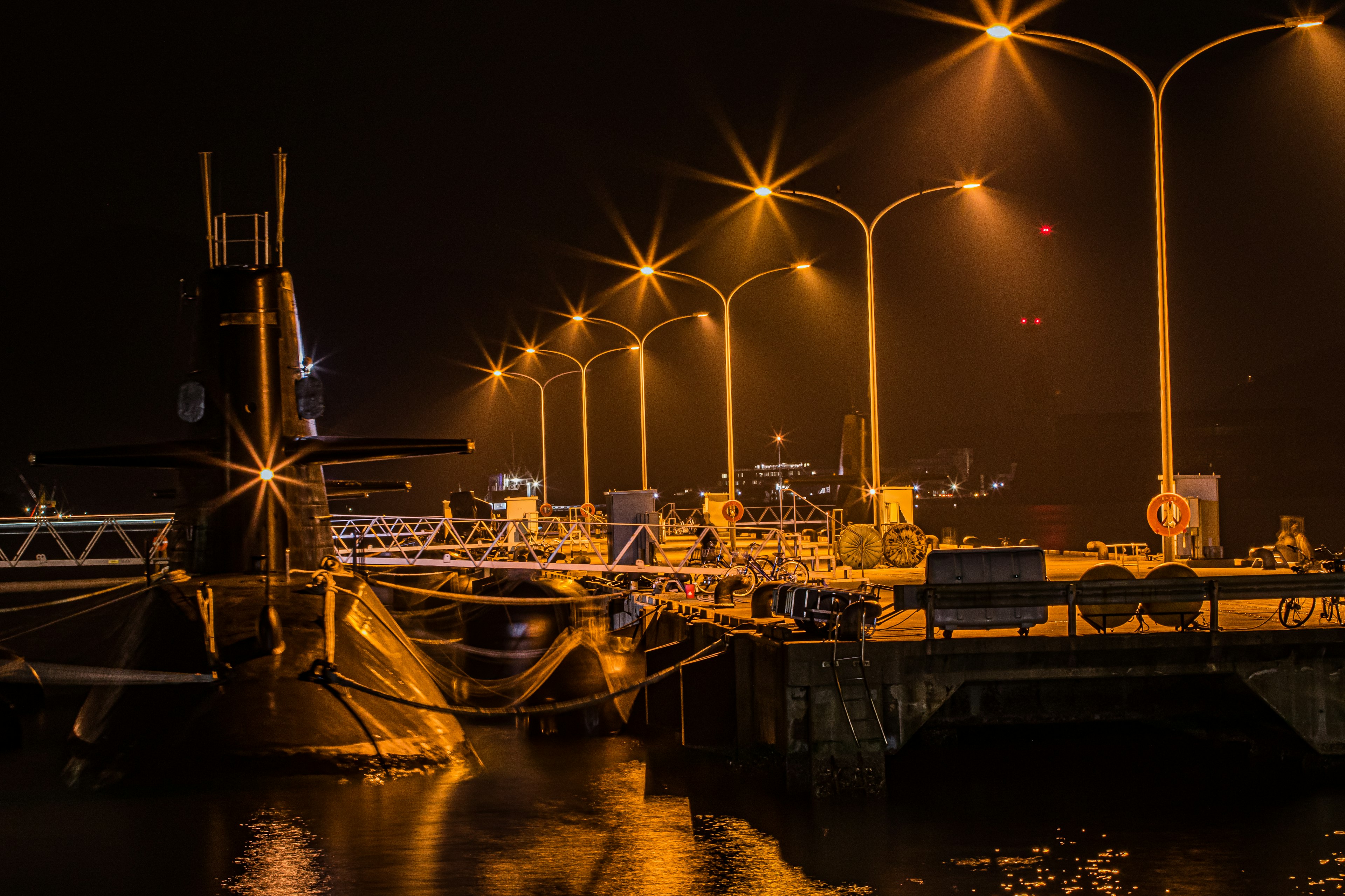 Submarine at night in a harbor with bright streetlights