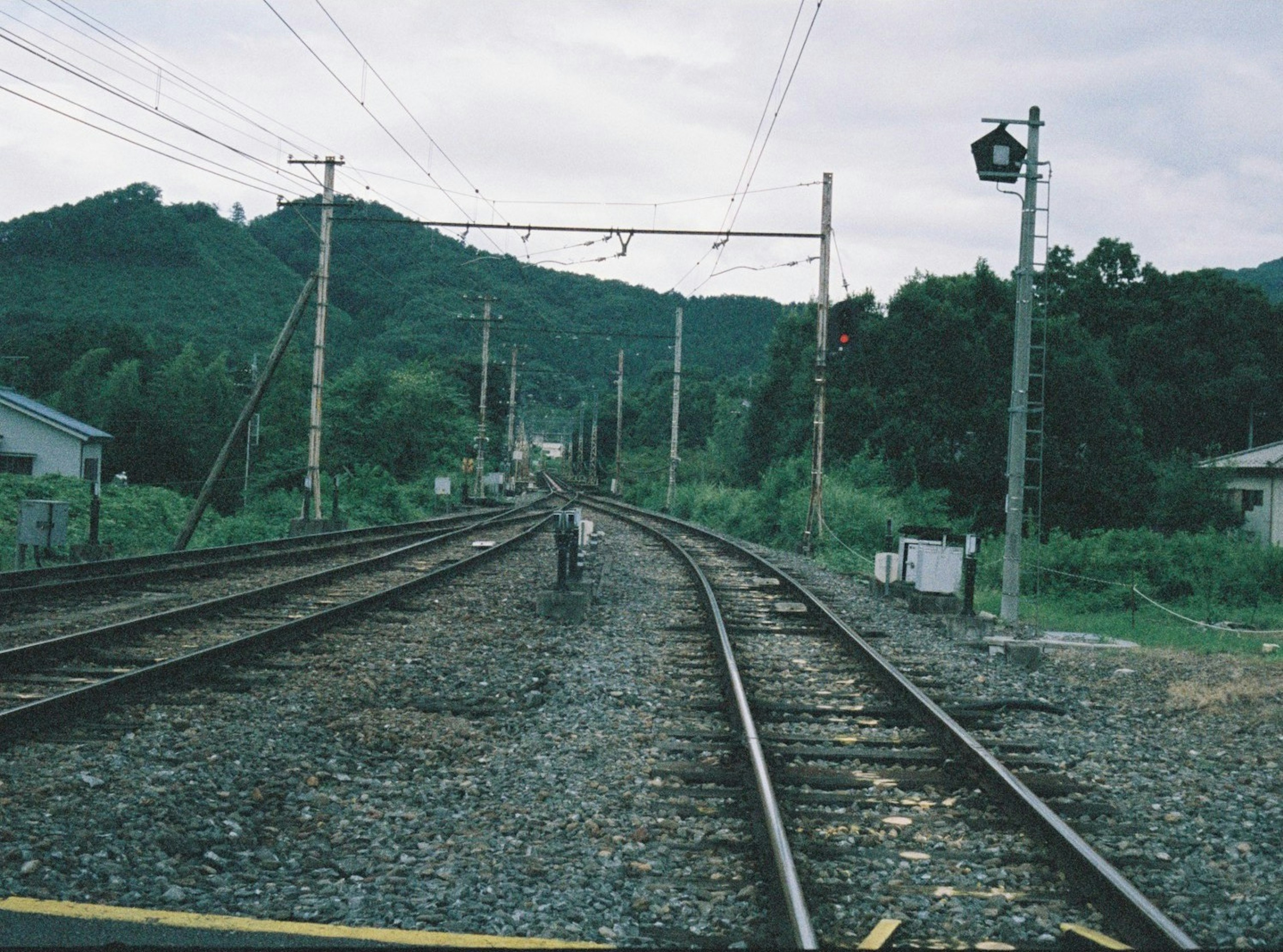 鉄道の線路が曲がり、背景に山が見える風景