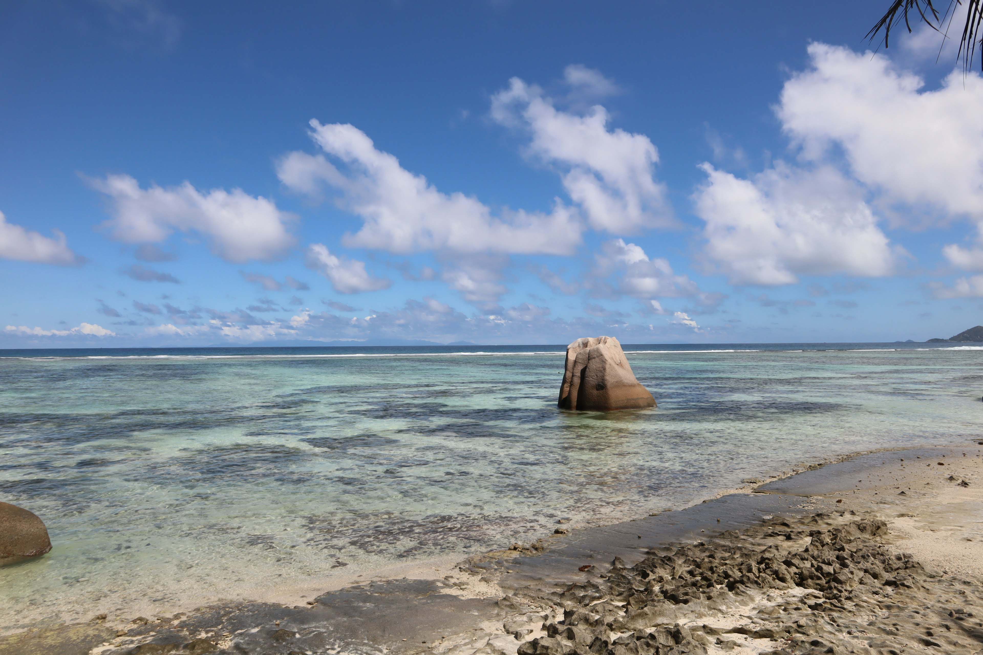 Vista de playa escénica con cielo azul agua clara y una formación rocosa prominente