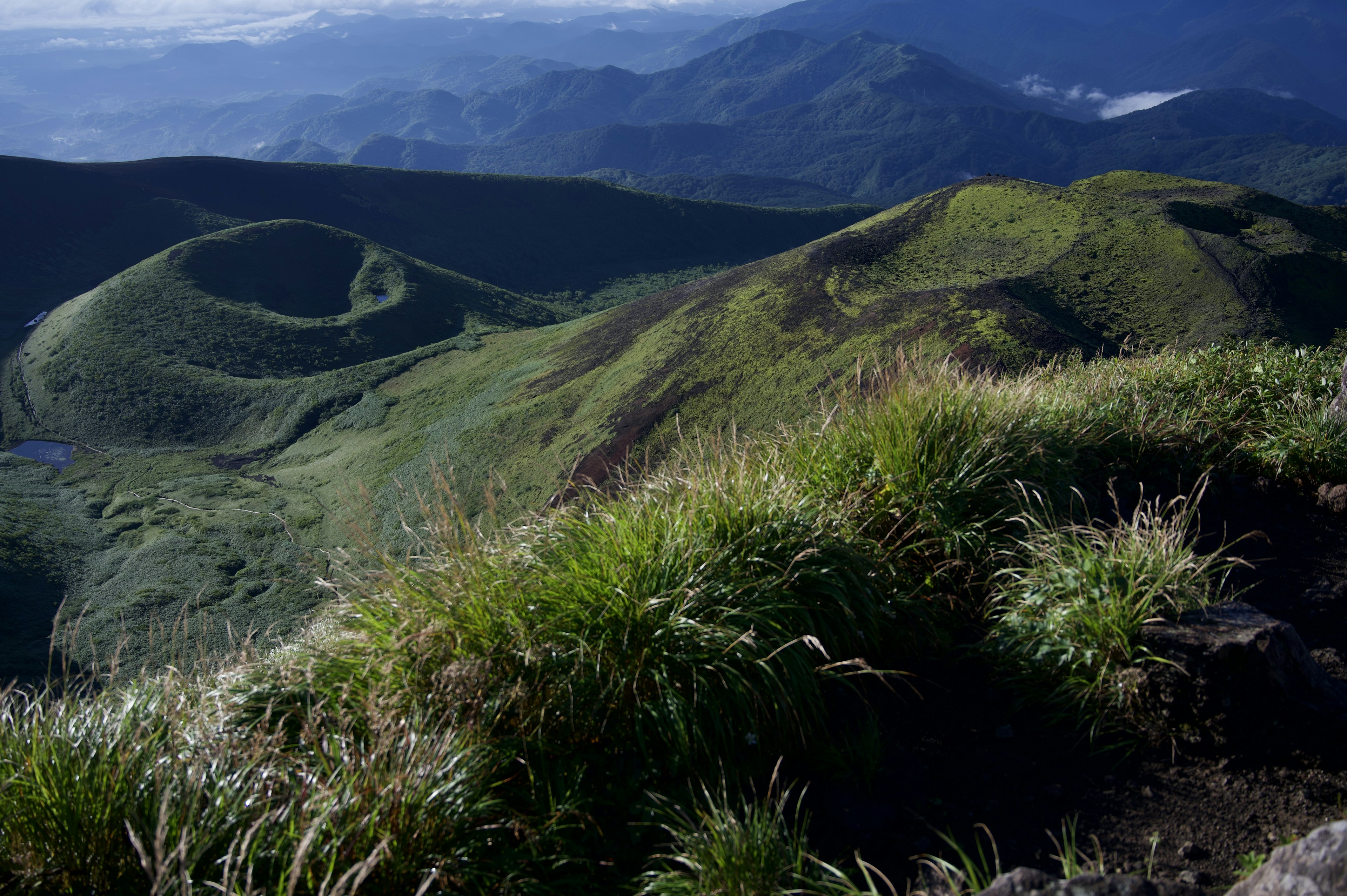 Lush green hills with distant mountains in the background