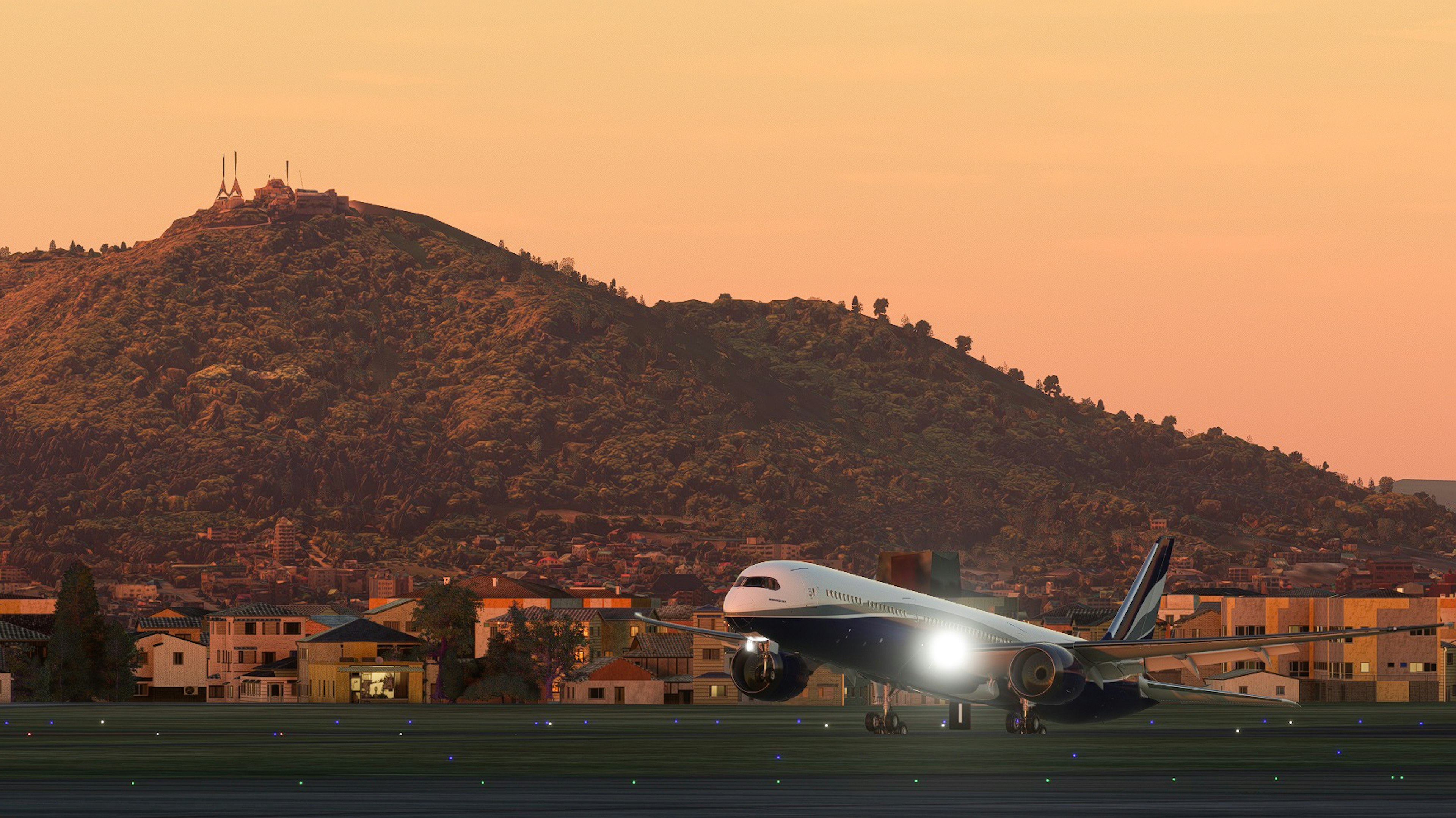 An airplane taking off on a runway with a mountain backdrop during sunset