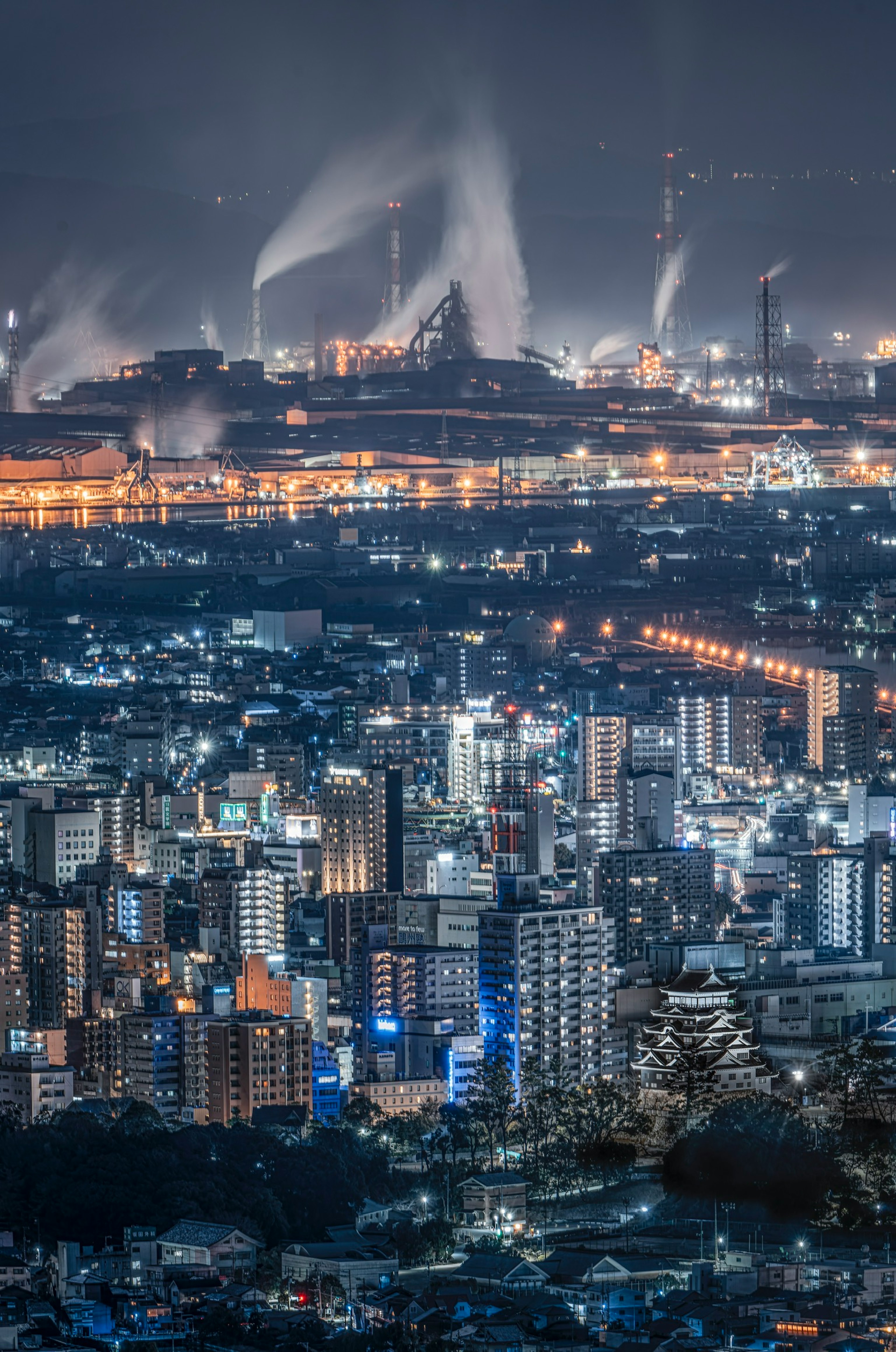 Nachtansicht einer Stadt mit Industriegebiet im Hintergrund